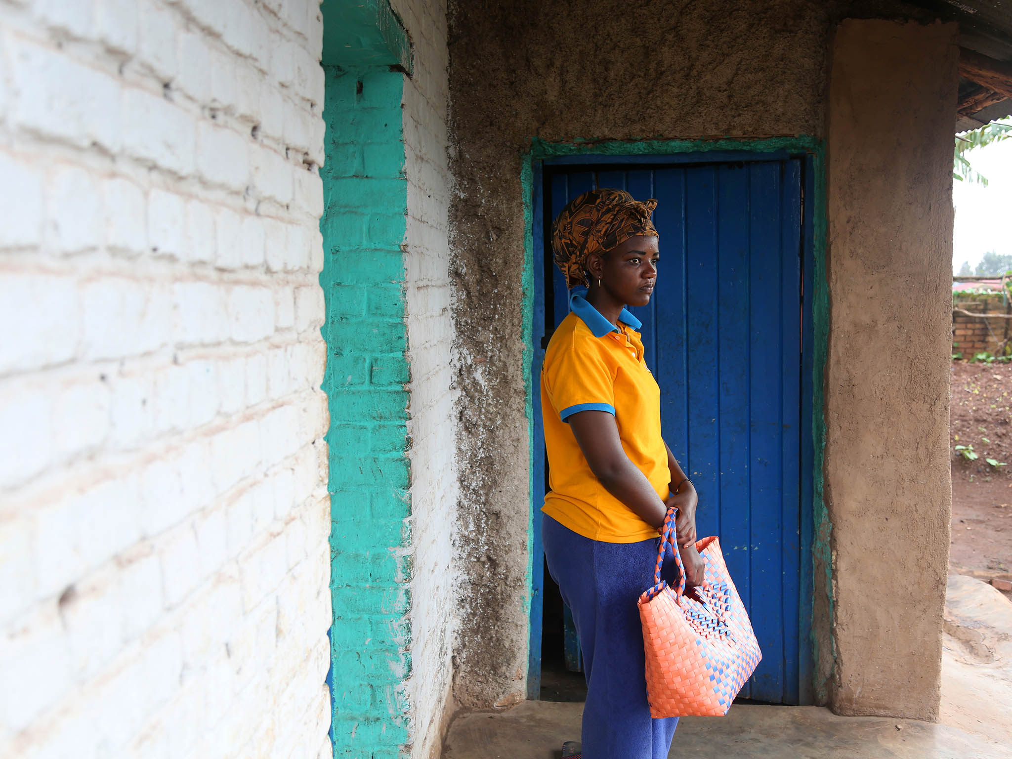 Outside the house she shares with her mother, Angel walks down the street to buy sugar in Ngoma Sector, Rwanda, in the southern part of the country near Huye