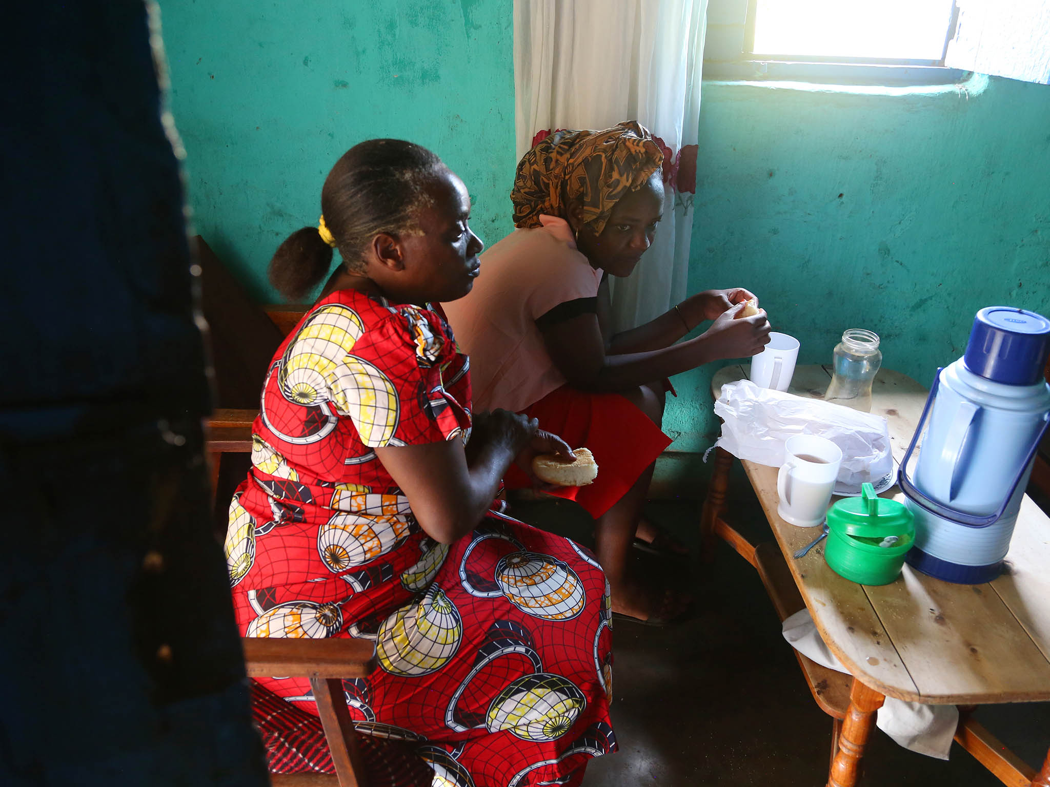 Angel eats bread and drinks tea with her mother Jacqueline, left, at their home before they go to church