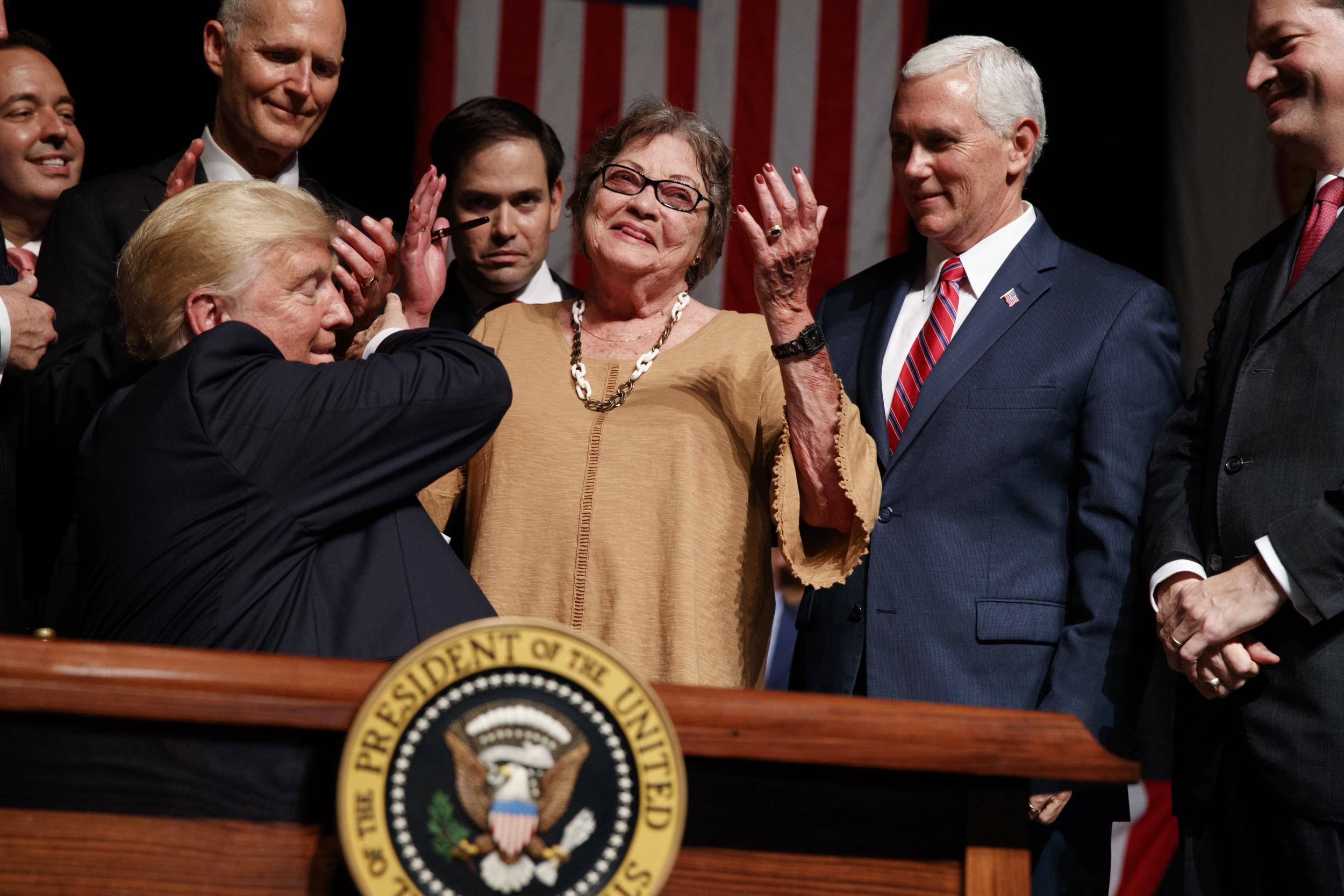 Trump hands a pen to a Cuban dissident after signing an executive order on Cuban police in Miami