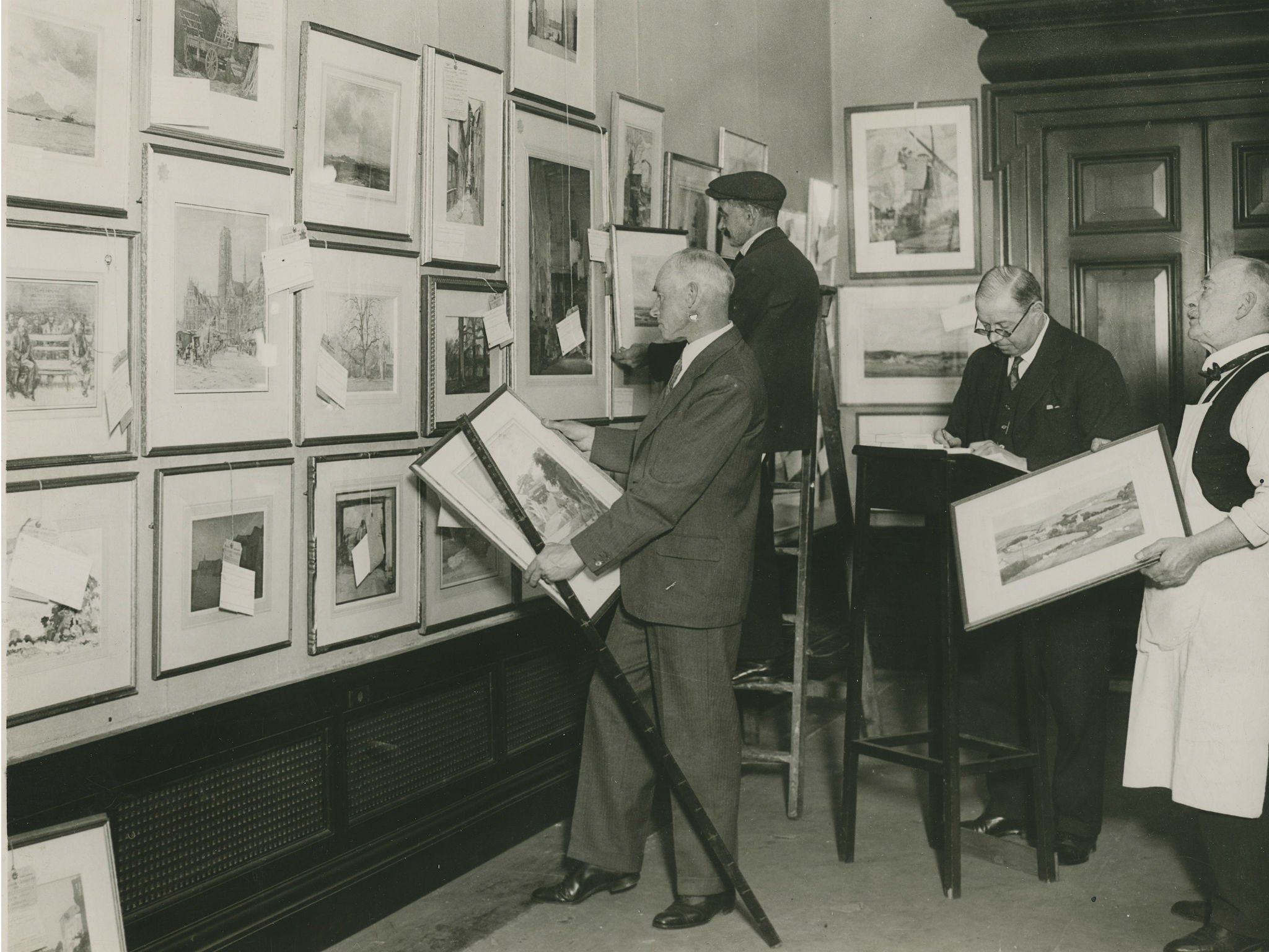 The 166th Summer Exhibition, 1934. William Russell Flint RA at work arranging the hanging of watercolours in one of the galleries.