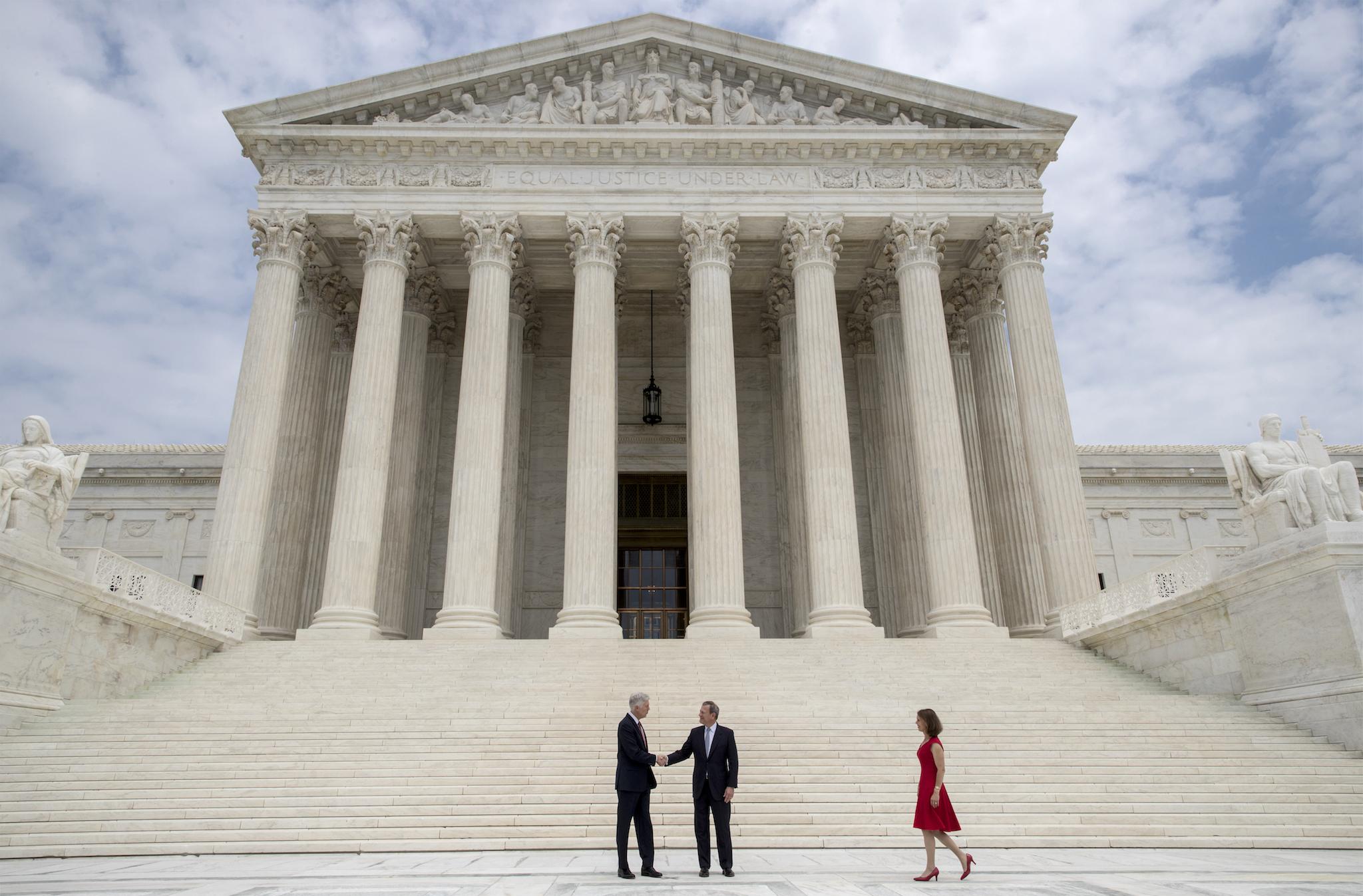 Associate Supreme Court Justice Neil Gorsuch shakes hands with Chief Justice John Roberts