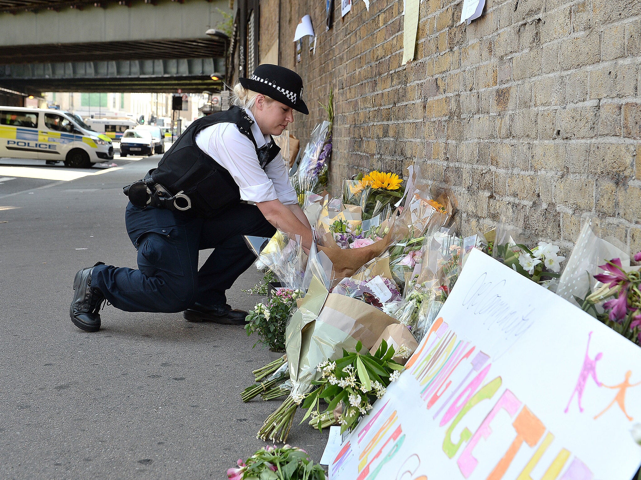 A police officer lays flowers passed over by a member of the public, close to Finsbury Park Mosque in north London