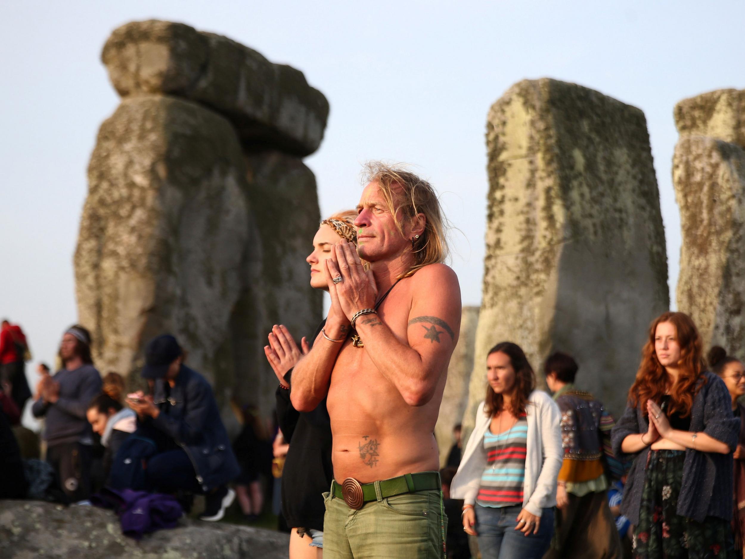 People clasp their hands together as the sun comes up on the Summer Solstice
