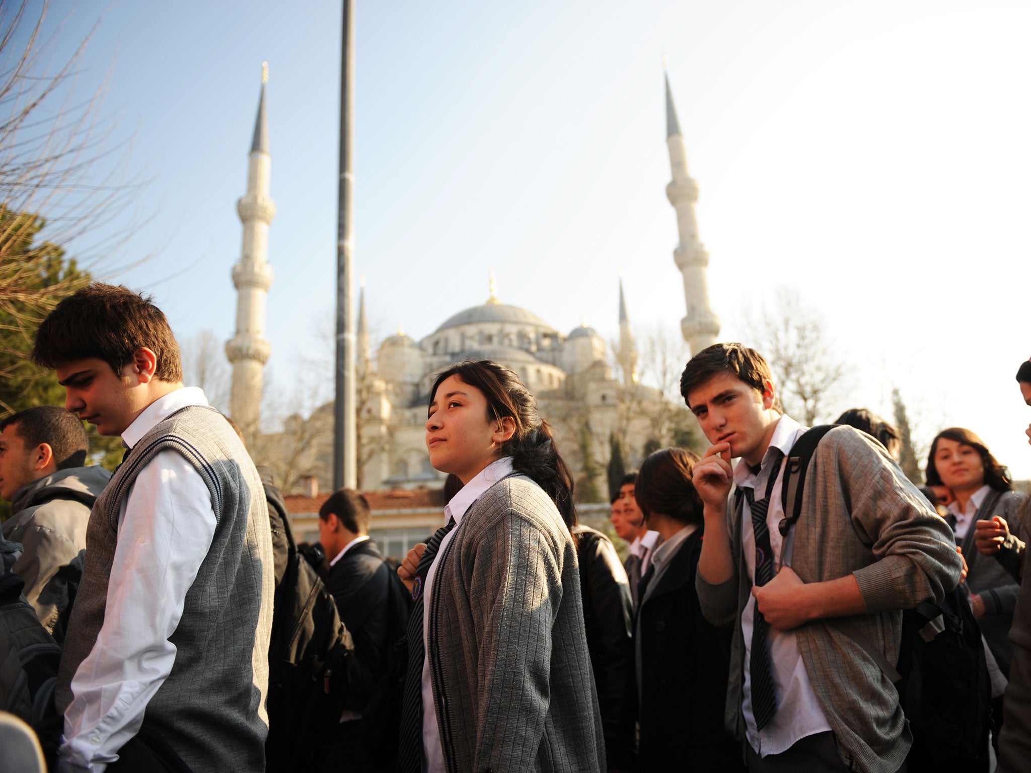 Turkish students listen to their teacher before entering their high school early in the morning in Istanbul on March 23, 2012.