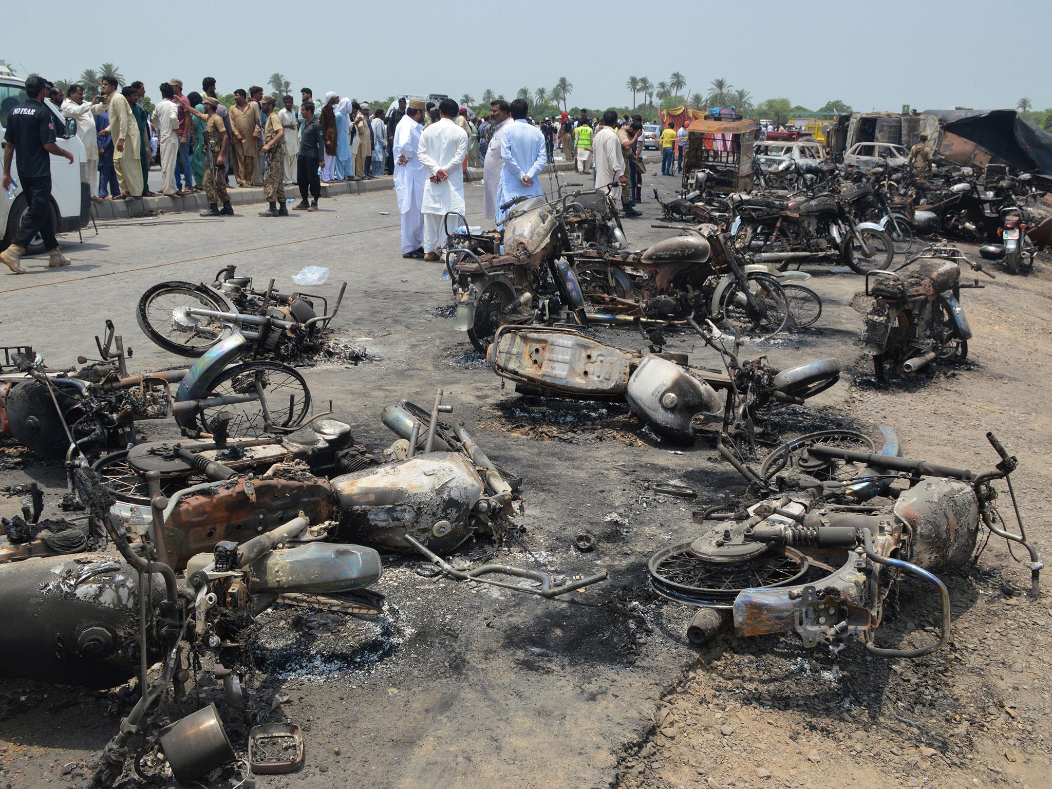 People gather behind burnt motorcycles and vehicles at the scene of the accident on the outskirts of Bahawalpur (EPA/Faisal Kareem)