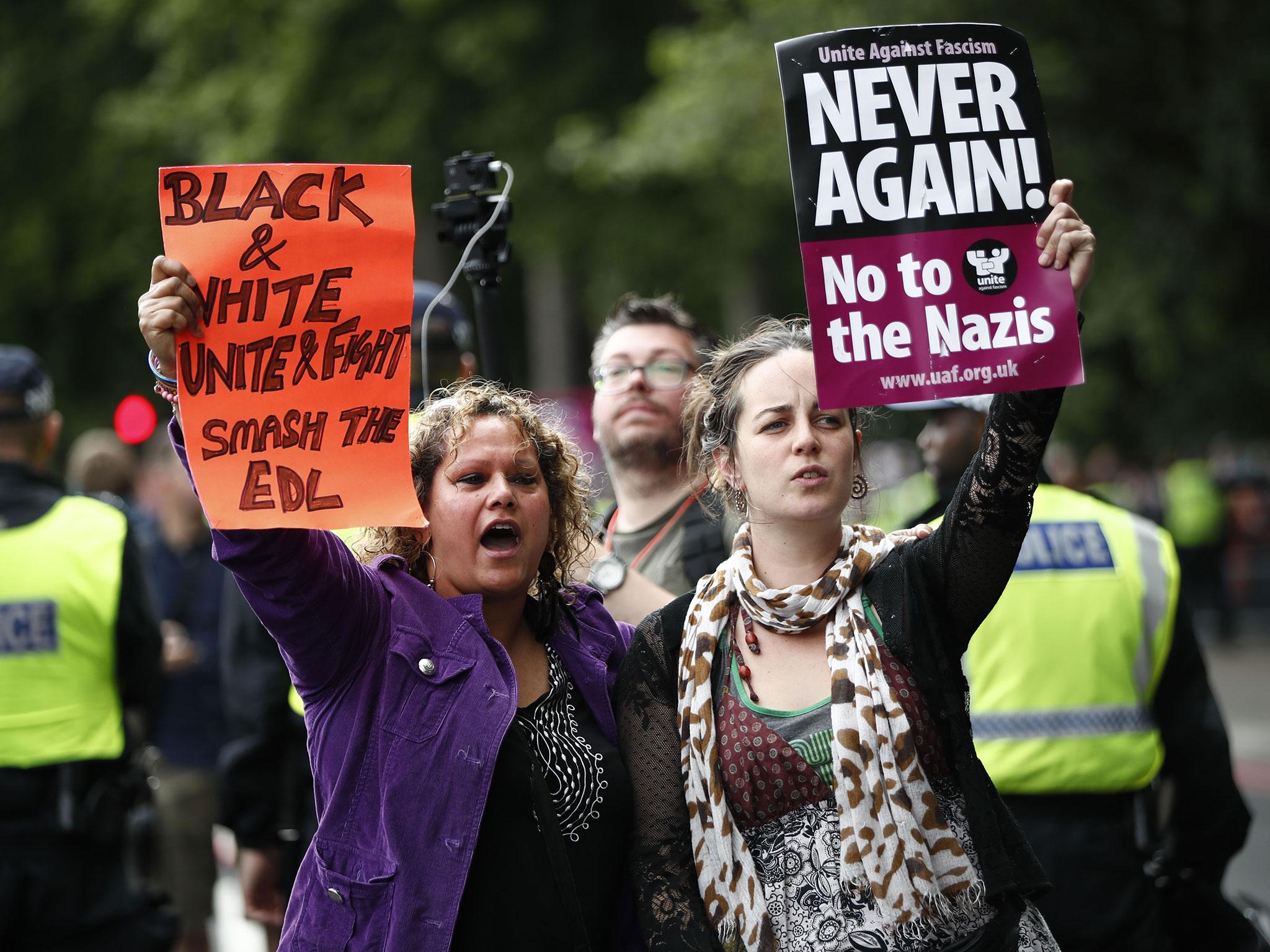 Counter-demonstrators hold up placards reading 'Never again! No to the Nazis' and 'black and white, unite and fight, smash the EDL' as the English Defence League (EDL) gather for a demonstration in central London