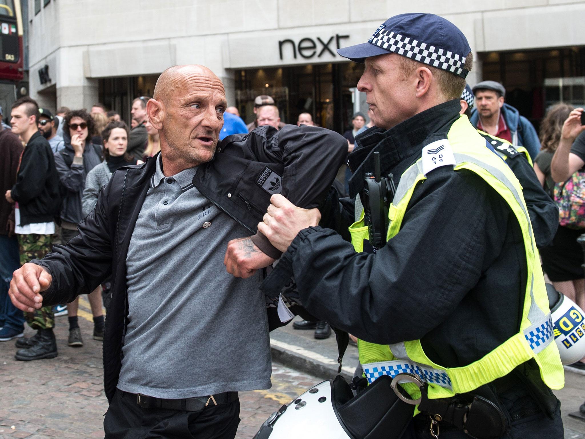 A police officer scuffles with a man as members of the far-right anti-immigration English Defence League (EDL) march from Victoria Embankment to Charing Cross Station under heavy police guard, in London