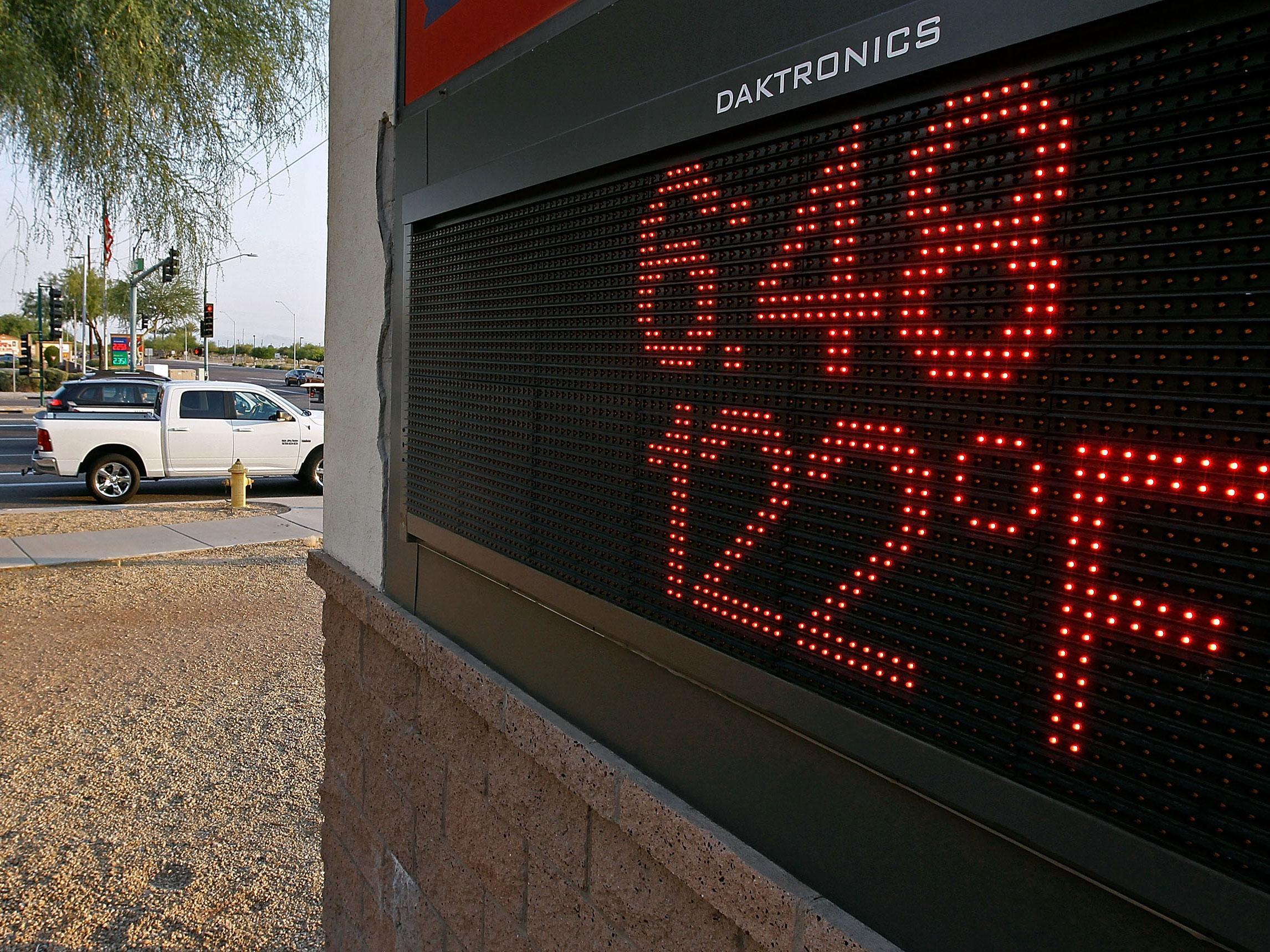 Motorist stop at an intersection where a sign displays the temperature in Phoenix, Arizona