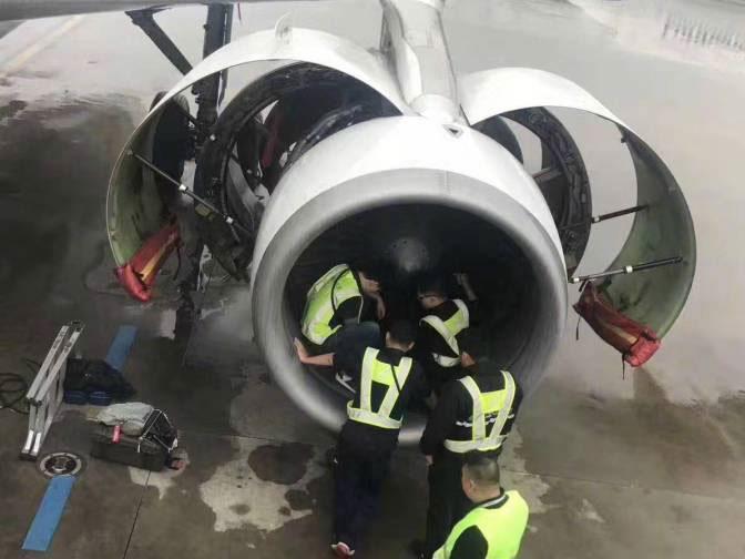 Officials examine the aircraft engine after an elderly woman threw in coins for good luck