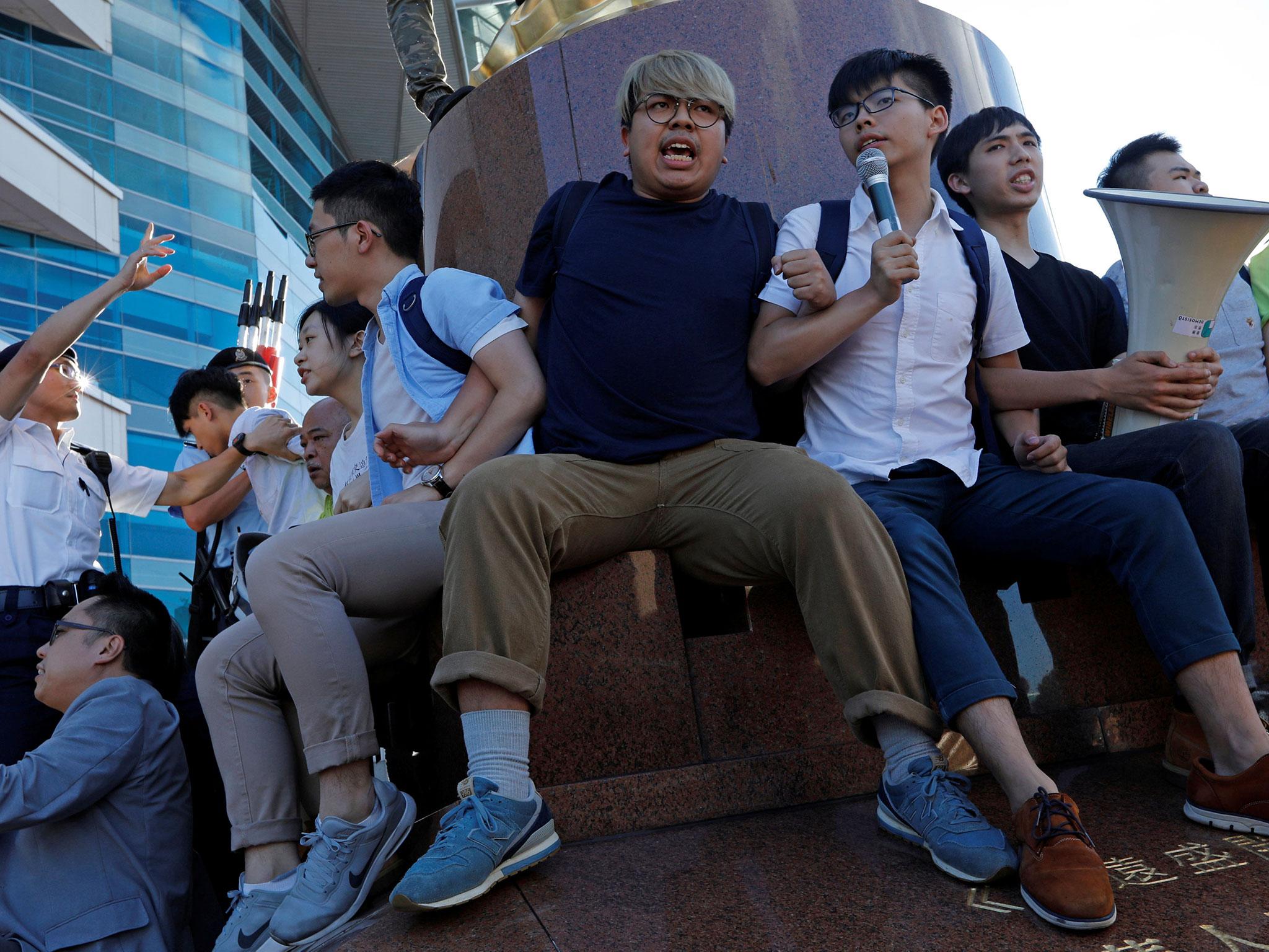 Pro-democracy activist Joshua Wong (upper right) chants slogans in front of the Golden Bauhinia sculpture during a protest to demand full democracy ahead of the 20th anniversary of the handover from Britain to China