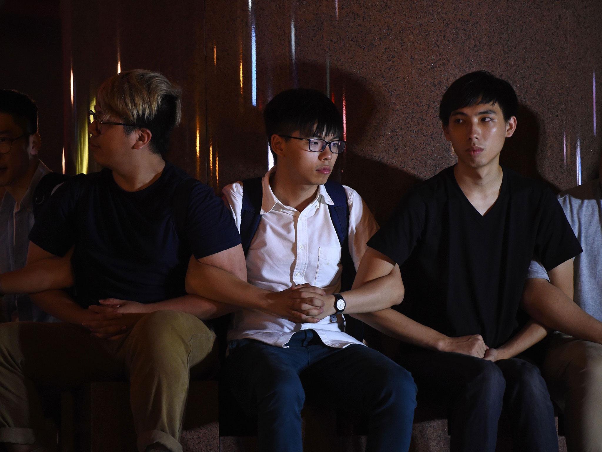 Pro-democracy campaigner Joshua Wong and other demonstrators link arms as police prepare to remove them from the base of the Golden Bauhinia statue