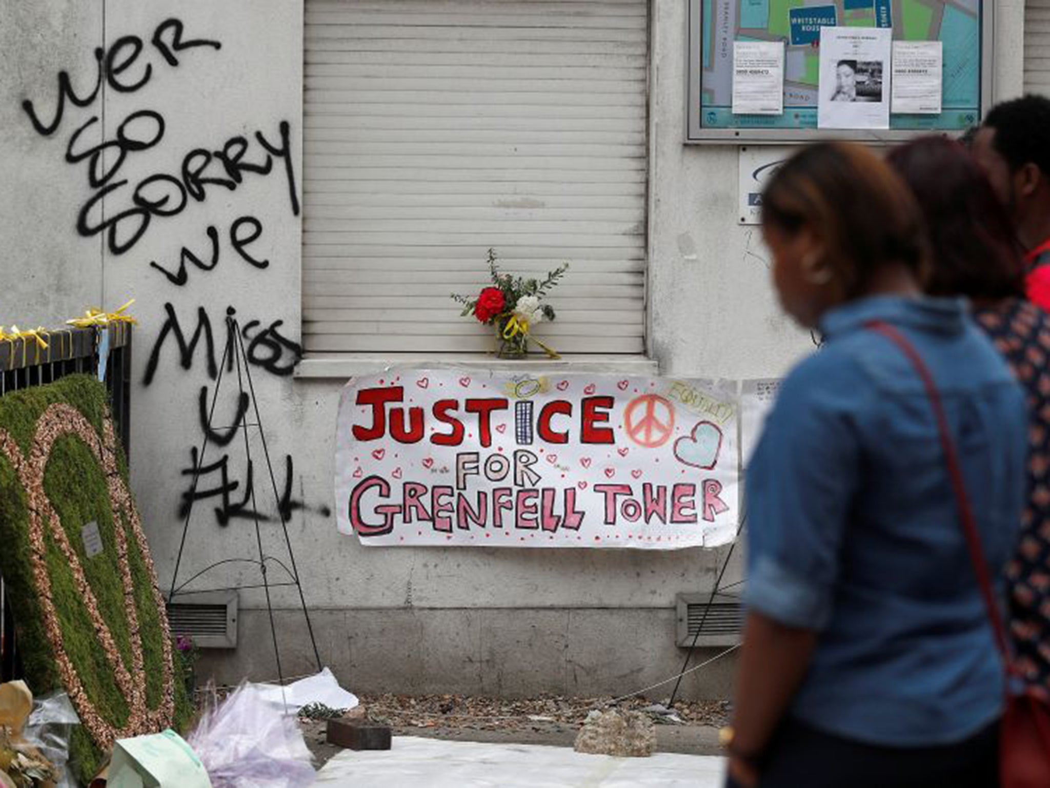 Passers-by look at posters and messages of condolence for the victims of the Grenfell Tower fire