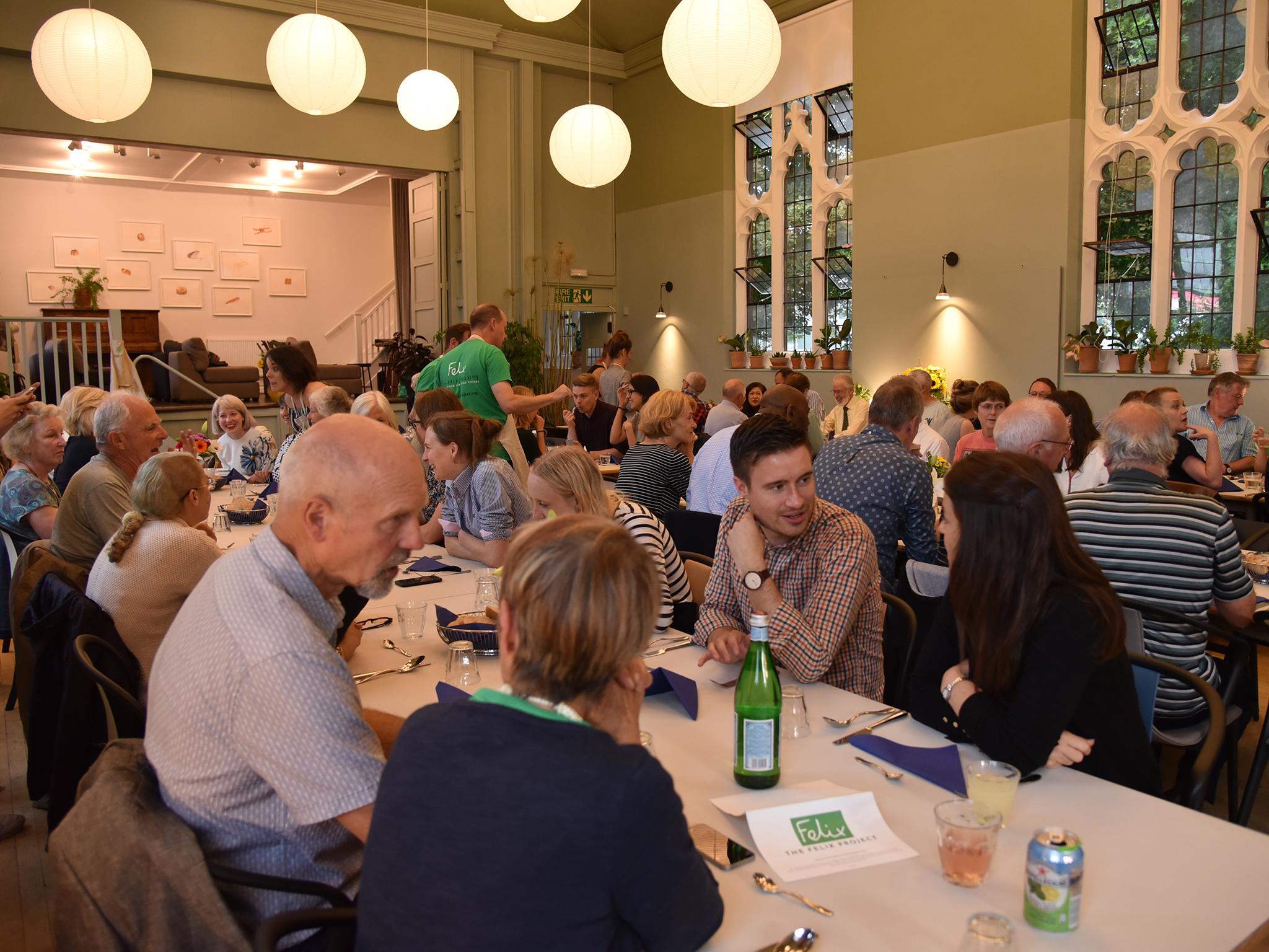 Volunteers from the Felix Project sit down to dinner at the St Cuthbert's Centre