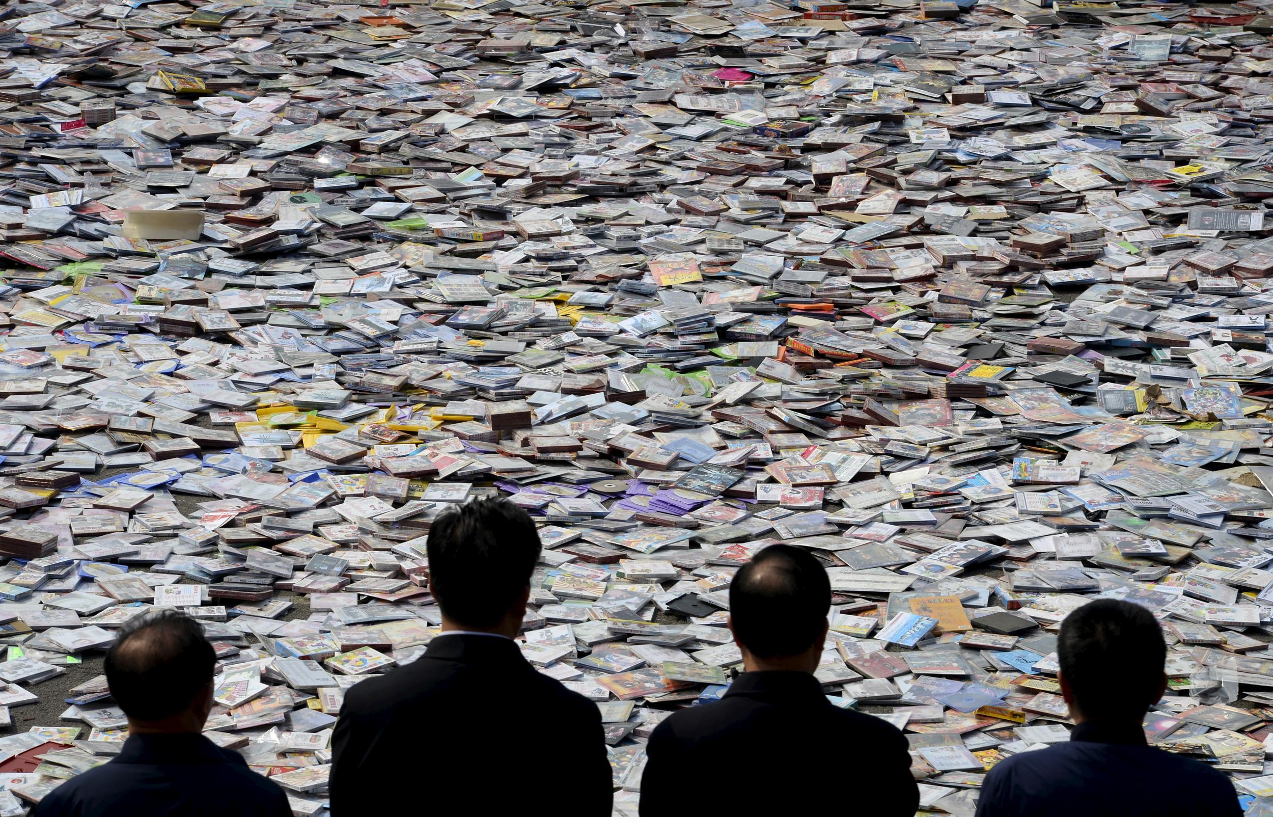 Government officials look on as pirated publications, including DVDs, CDs etc, are placed on the ground before being destroyed, during a campaign against piracy in Taiyuan, Shanxi province April 20, 2015