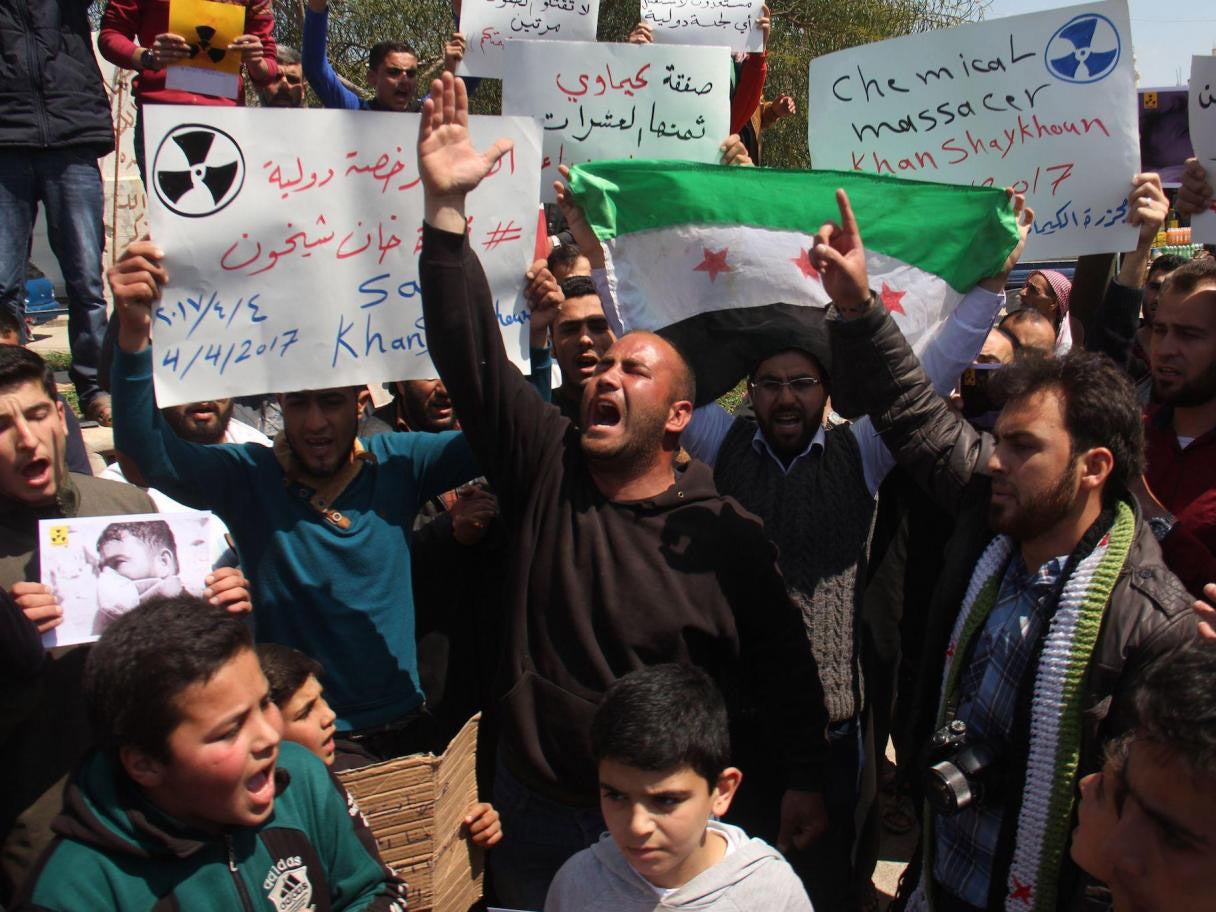 Syrian residents of Khan Sheikhun hold placards and pictures on 7 April during a protest condemning a suspected chemical weapons attack on their town that killed at least 86 people