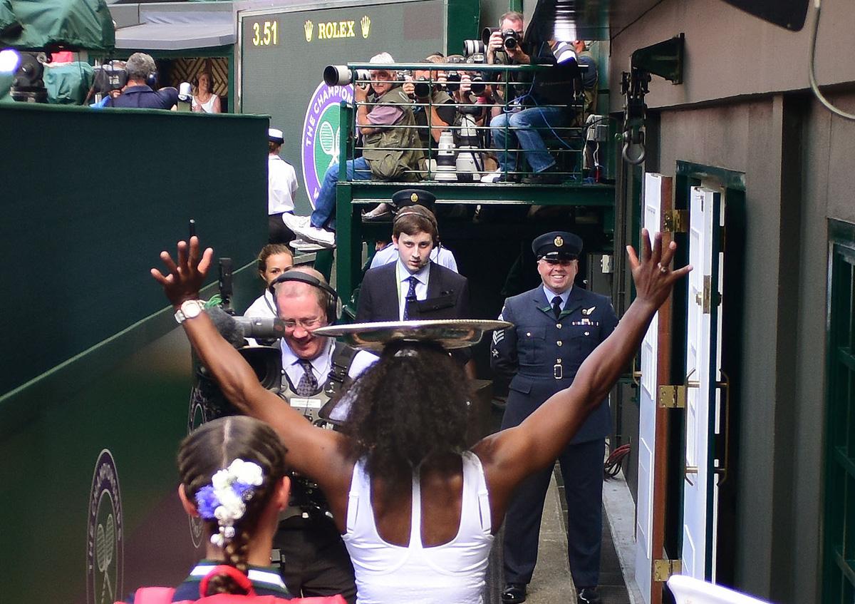 Serena Williams balances the Venus Rosewater Dish on her head with no hands as she walks off Centre Court.
