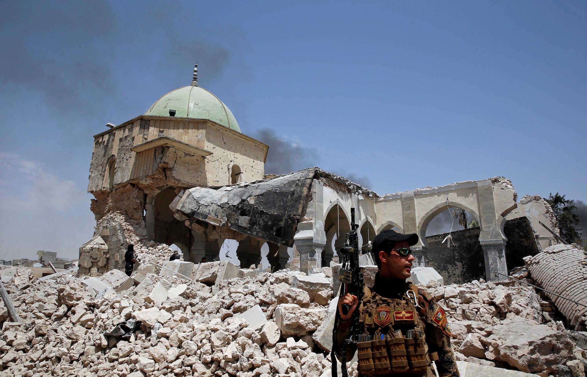 Iraqi forces' member of Emergency Response Division holds a weapon in front of the ruined Grand al-Nuri mosque in the Old City in Mosul. The refugee camp attack was one of a handful launched as Isis loses ground in the city