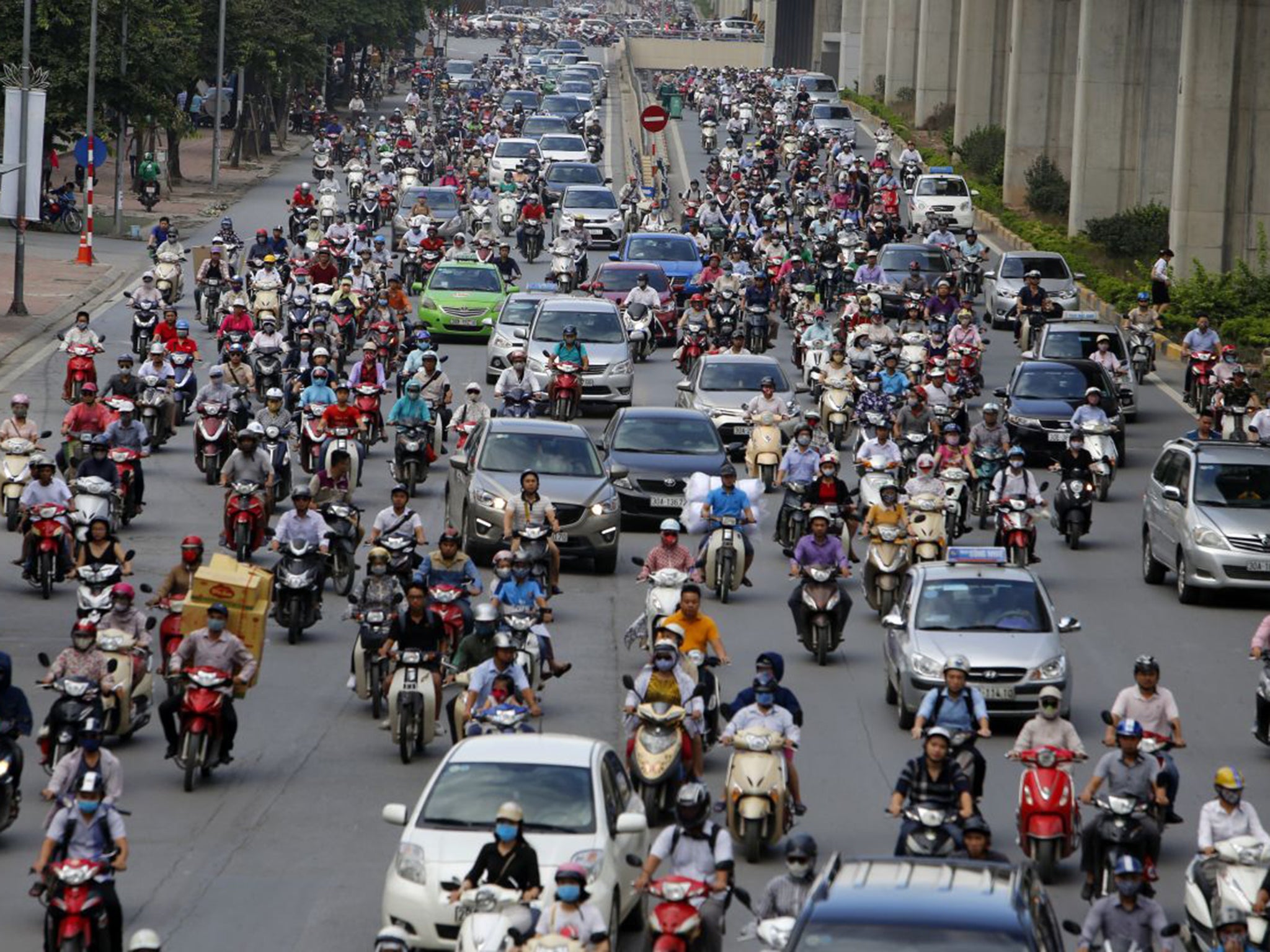 Motorbikes and cars fight for space on a street in Hanoi, Vietnam