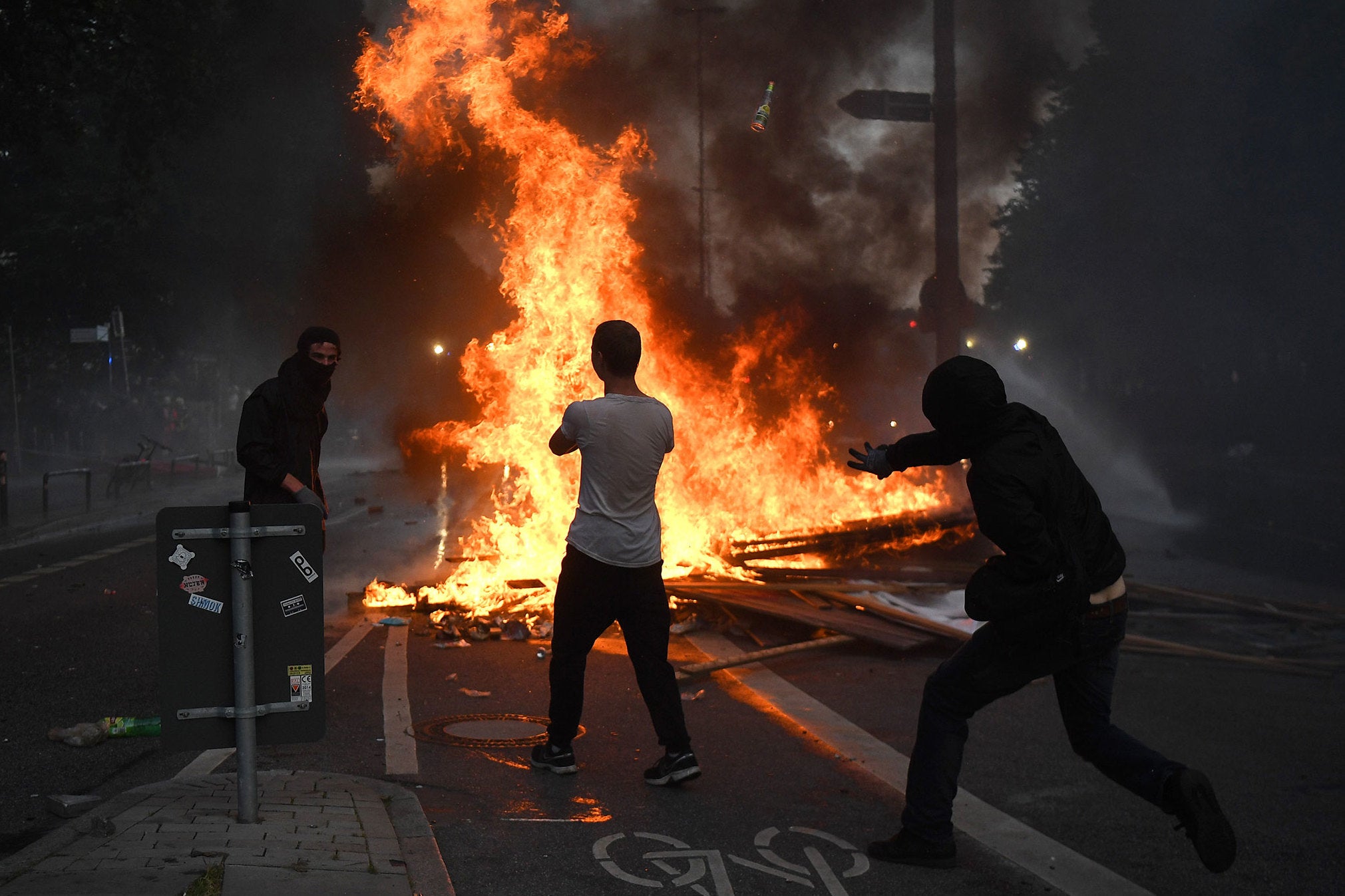 People gather near a fire burning in the middle of town during an anti-G20 protest in Hamburg.