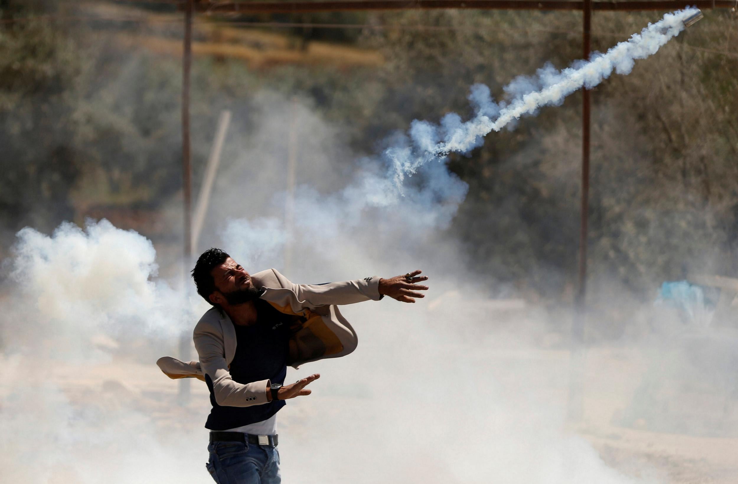 A Palestinian protester hurls back a tear gas canister fired by Israeli troops during clashes in the West Bank village of Beita, near Nablus, on 12 May 2017