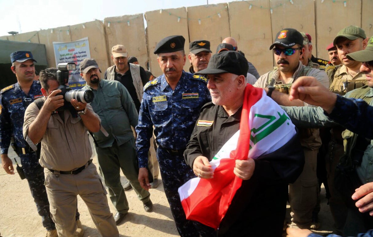 Prime Minister Haider al-Abadi, holding the Iraqi national flag, arrives in Mosul on Sunday