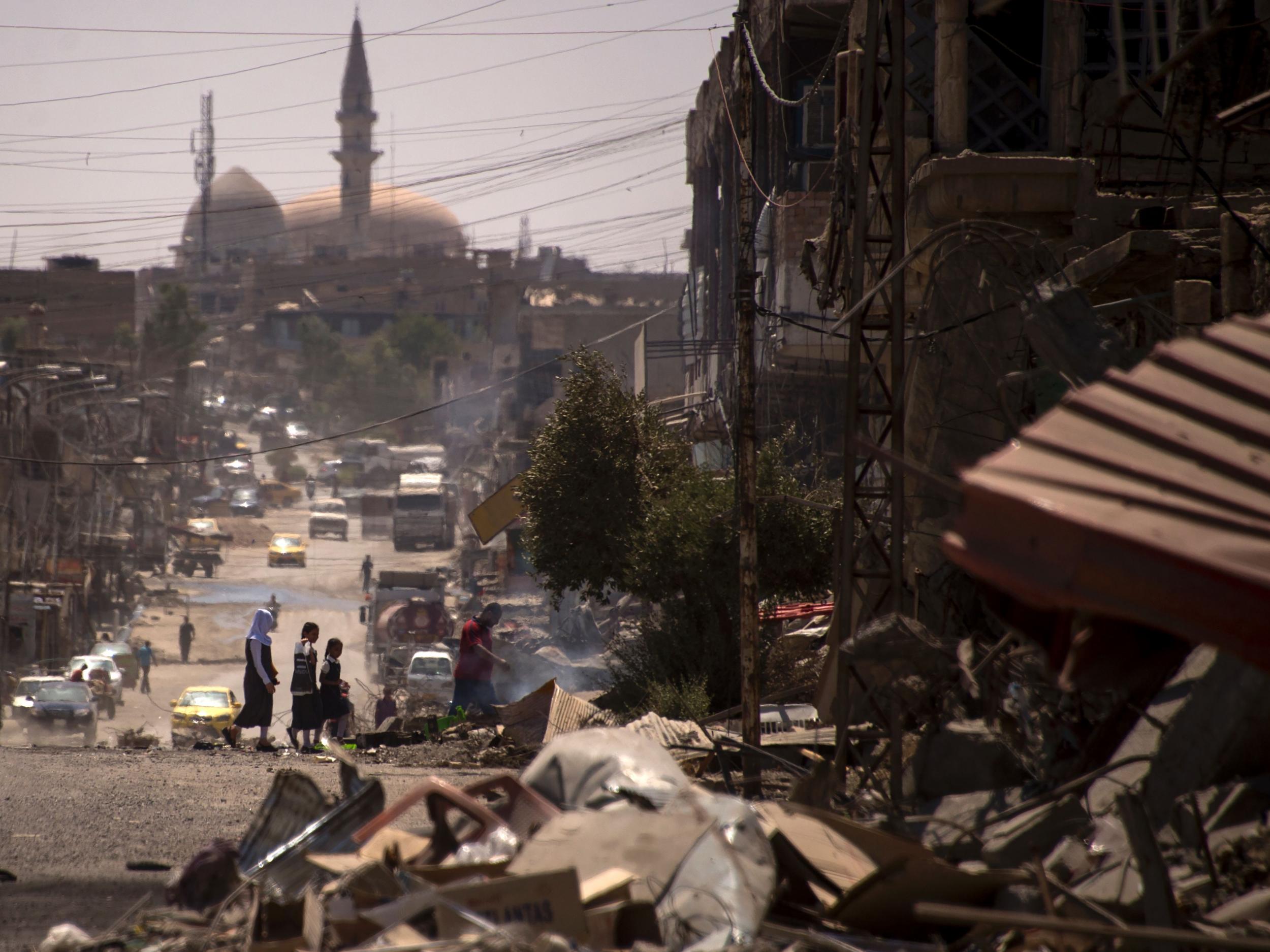 Iraqis walk on a damaged street in west Mosul a few days after the government's announcement of the liberation of the embattled city from Islamic State (IS) group fighters