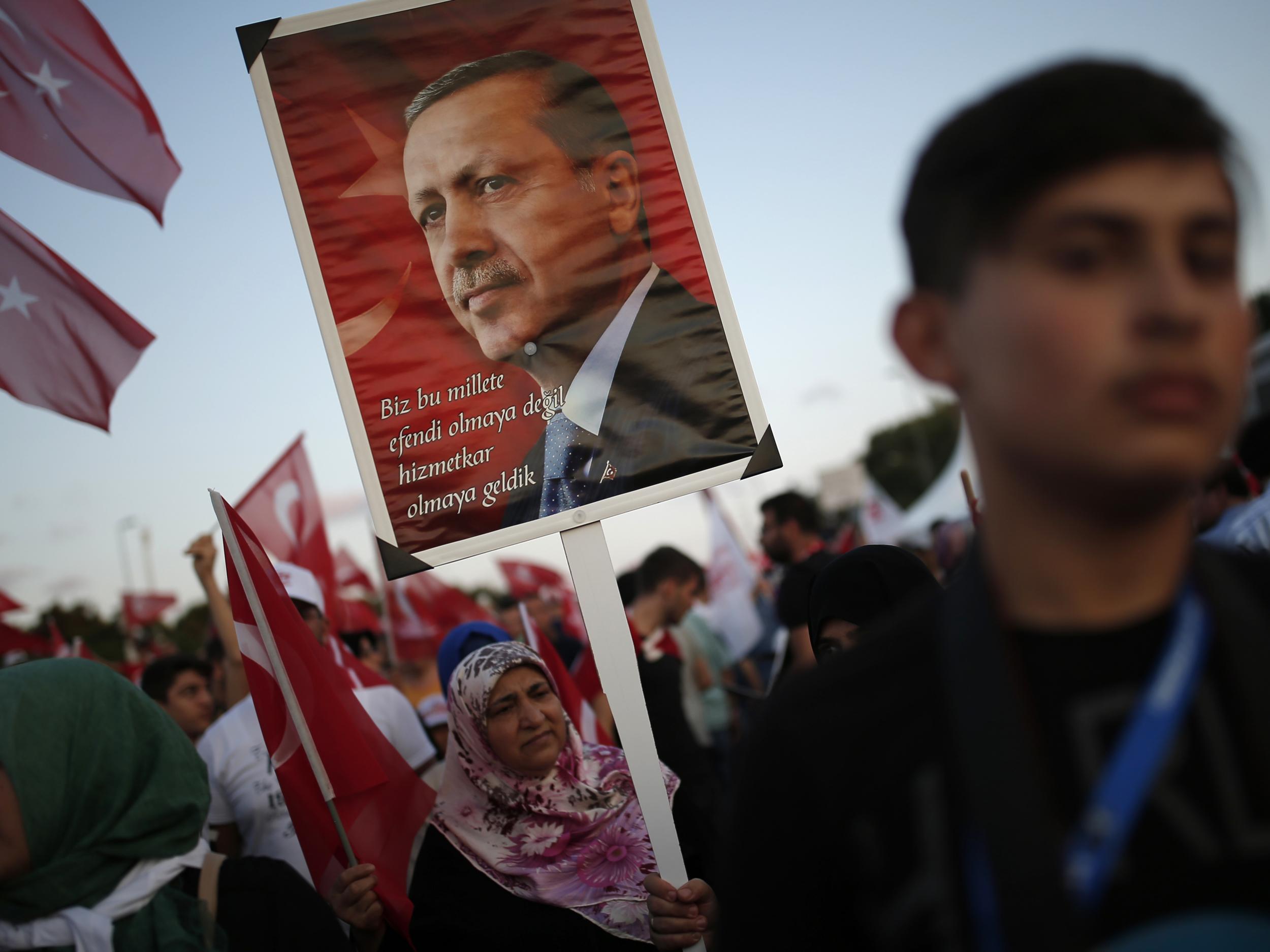 A woman holds placard depicting Turkish president Recep Tayyip Erdogan during 'National Unity March' to commemorate the one year anniversary of the July 2016 botched coup attempt