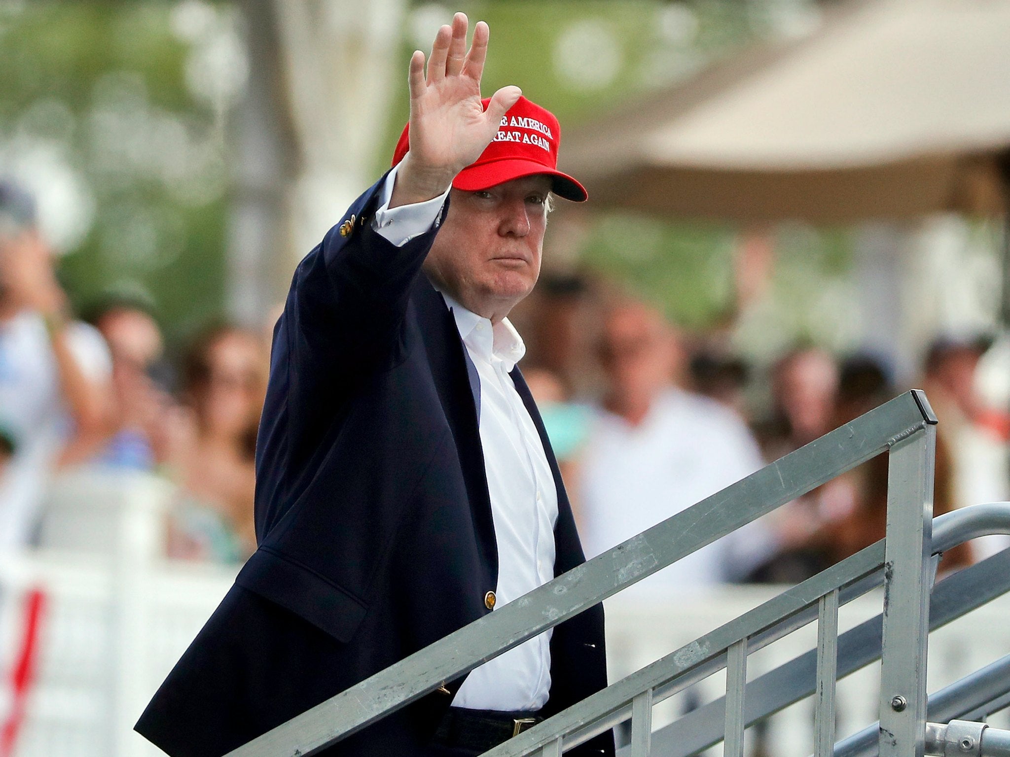 President Donald Trump waves to spectators as he walks up to his viewing booth on the 15th green at the Trump National Golf Club