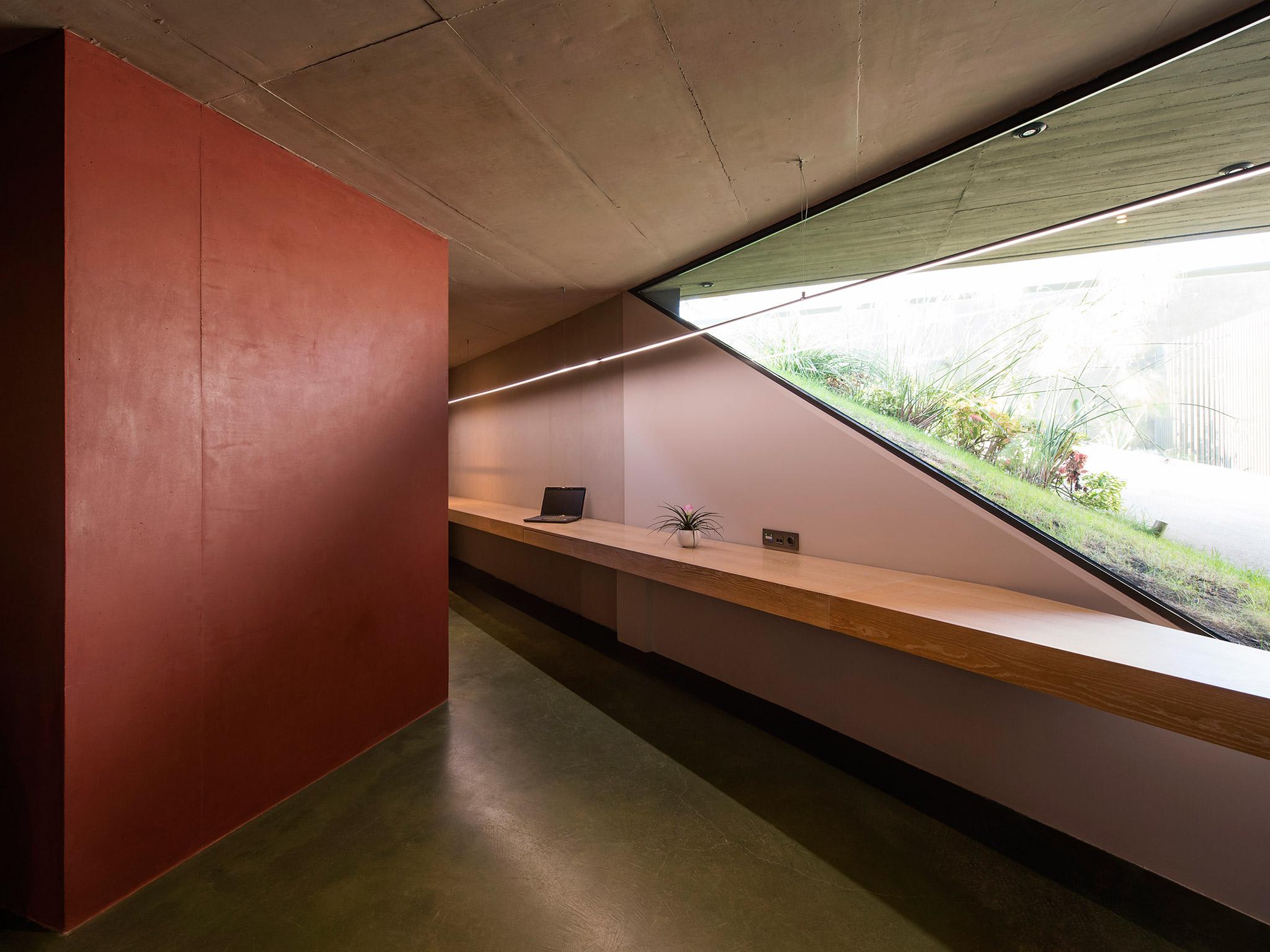 A red concrete wall inside the building