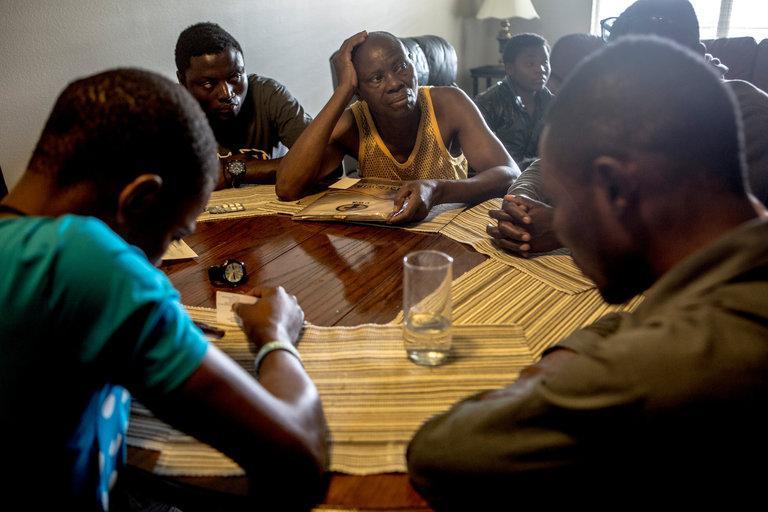 Watata Mwenda (centre) and his sons in an apartment in Fayetteville, Arkansas. They had just found out that a family member, John Feruzi, was not allowed to travel to the US