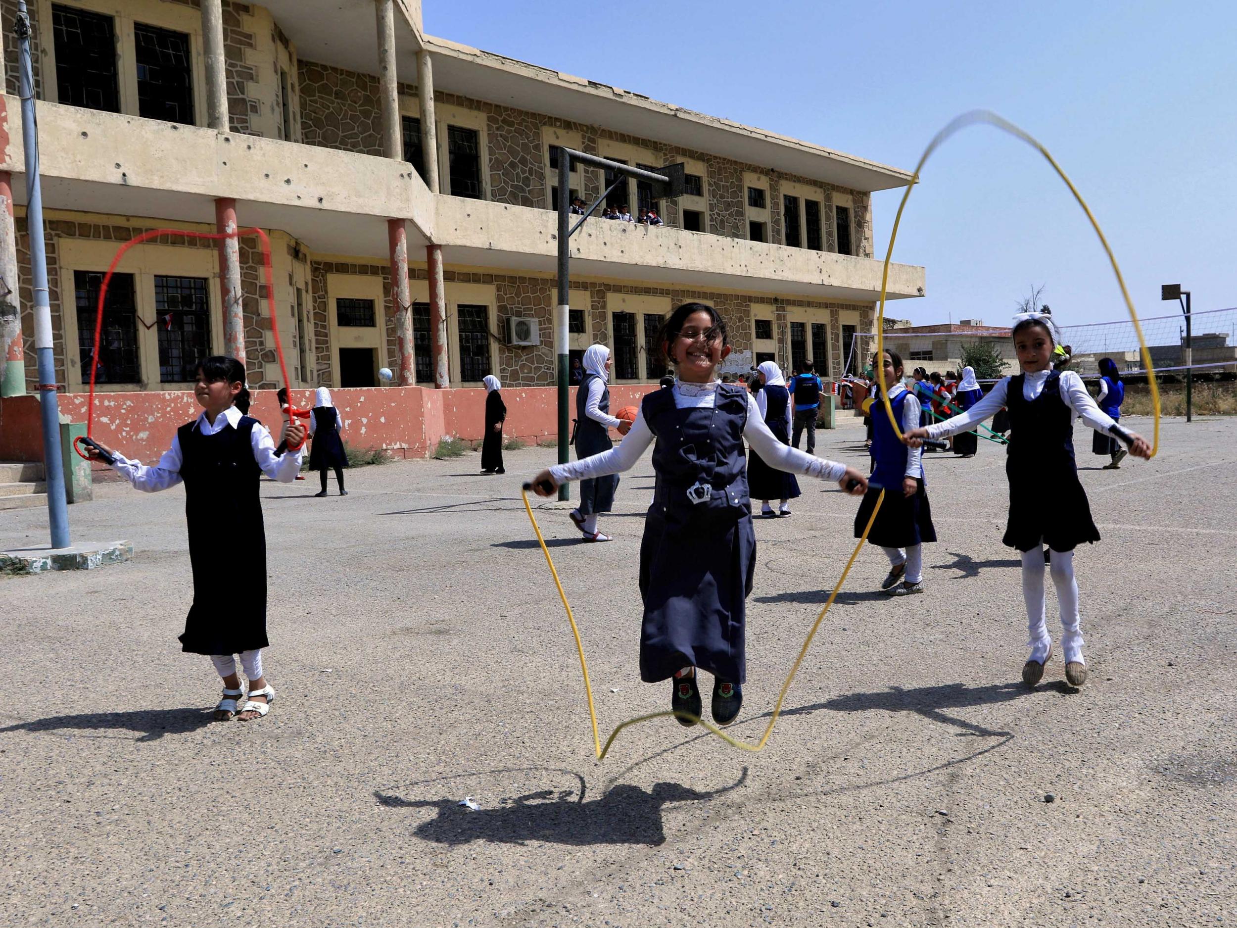 Iraqi girls play at a yard of a school in Mosul, Iraq