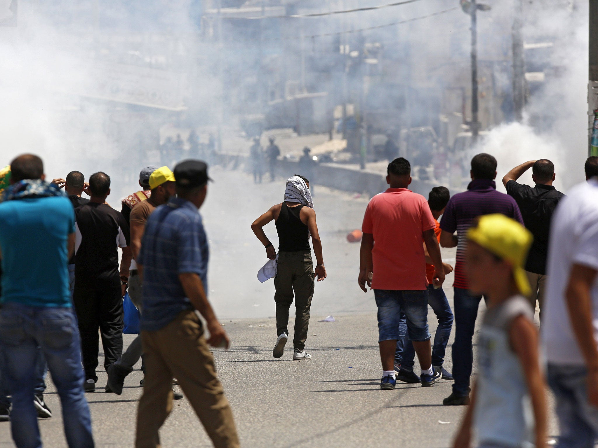 Israeli soldiers fire tear gas at Palestinian protesters during clashes after a protest at Qalandiya checkpoint near the West Bank city of Ramallah on 21 July