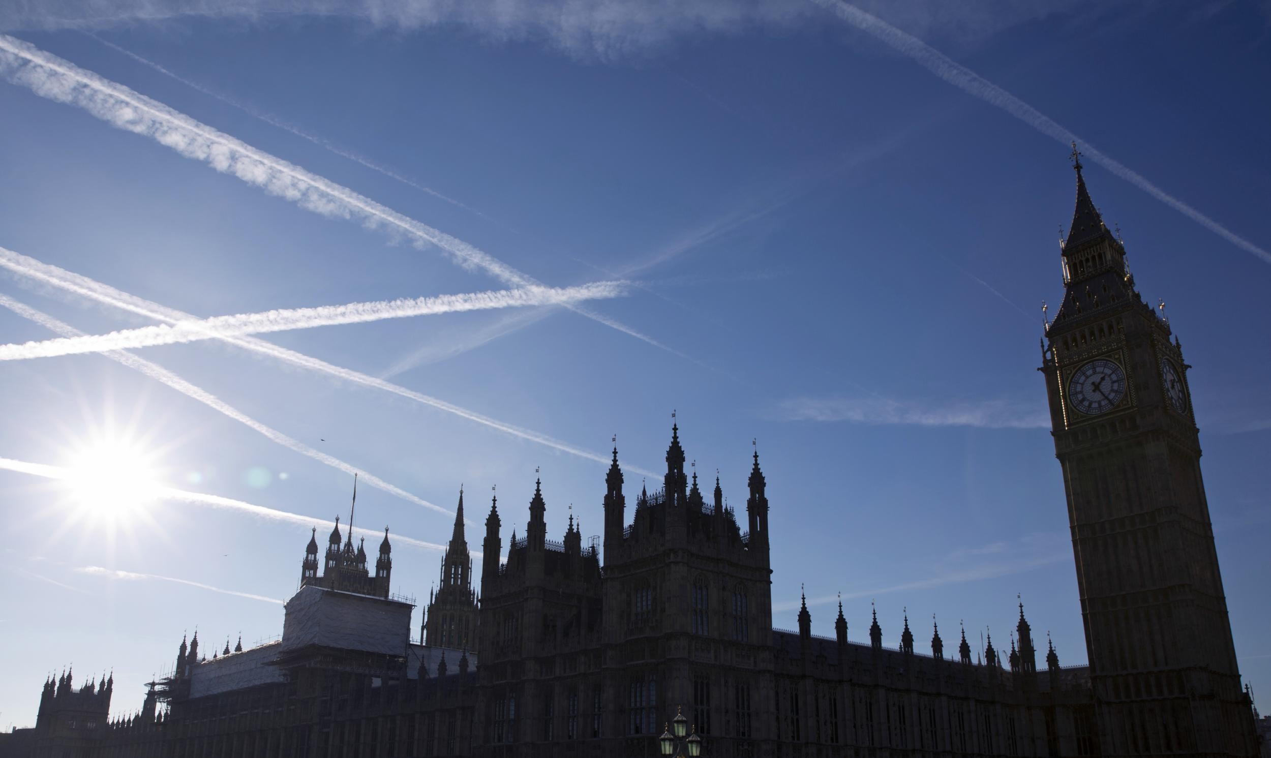 Contrails or vapour trails made by passing aircraft in the sky above the Houses of Parliament