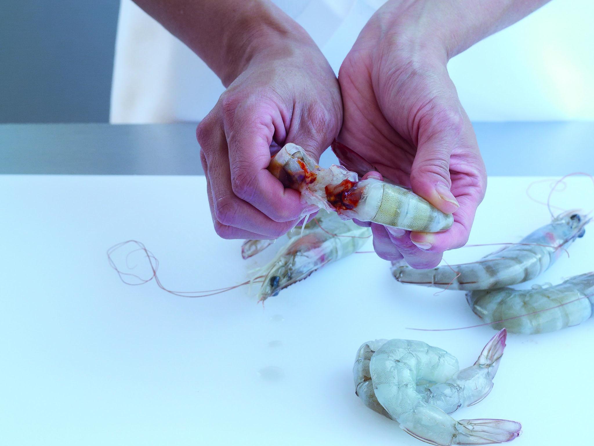 1. Hold the prawn by the tail. Using your other hand, twist the head and pull it away from the tail. Put the heads aside (they are full of flavour and, along with the tail shells, can be frozen and used later to make shellfish stock)