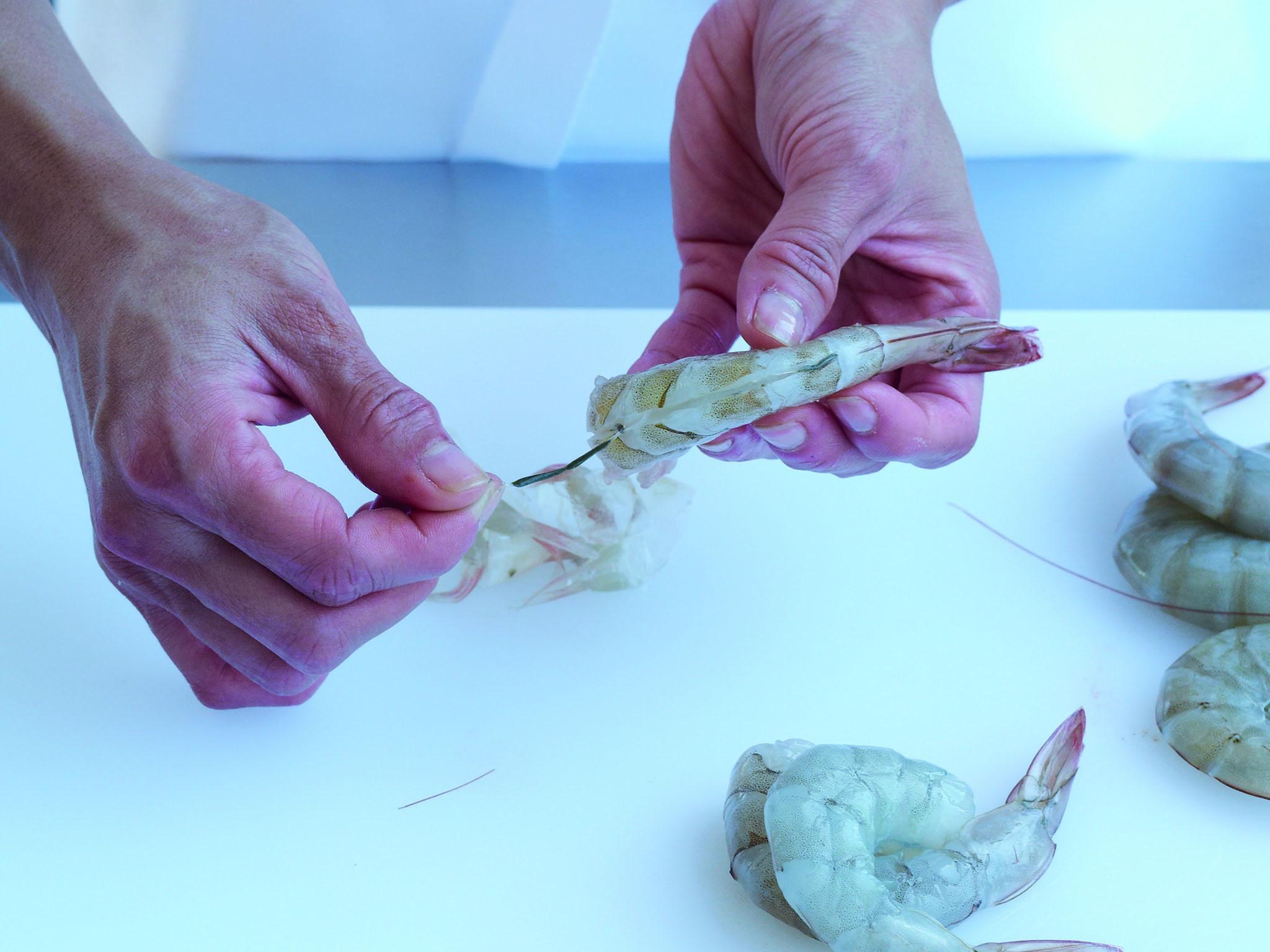 2. Cut down between the natural 2 halves of the prawn, halfway down, to butterfly the prawn, leaving the tail tip intact