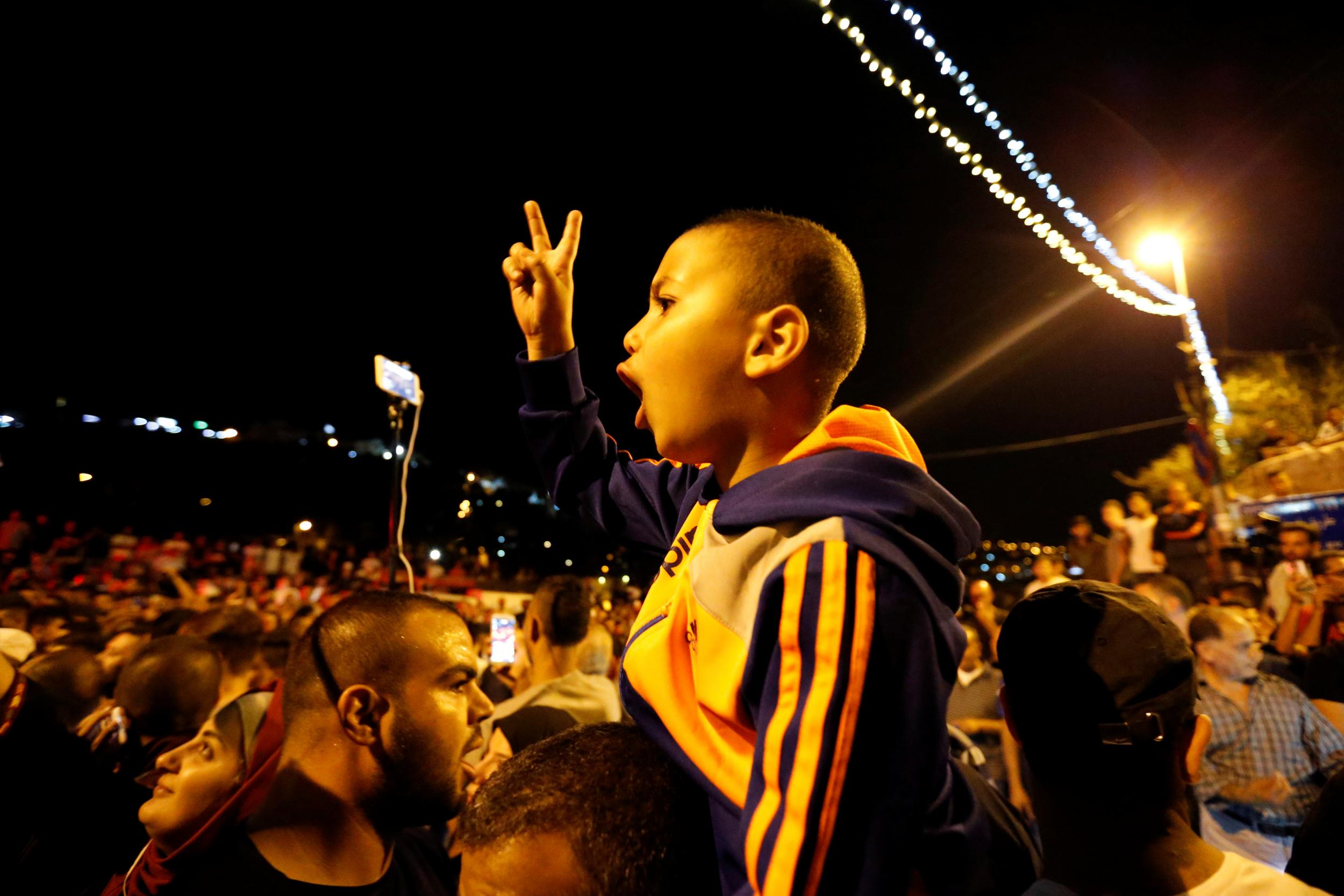 Palestinians celebrate outside the Lion's Gate at the entrance to Jerusalem's Old City following Israel's removal of security measures at a contested holy site in the early hours of 27 July 2017