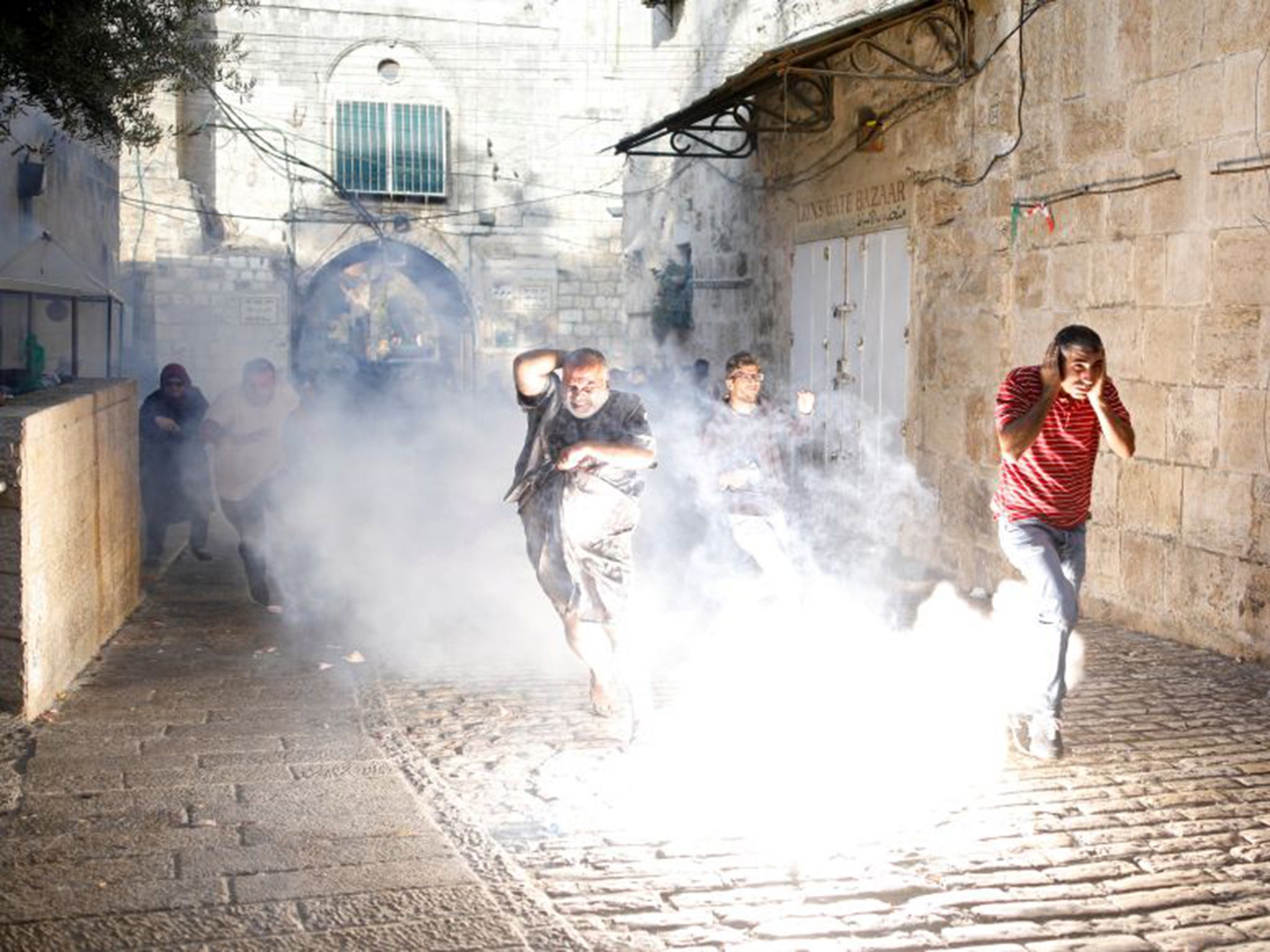 Palestinians scatter as a stun grenade explodes outside the Haram al-Sharif compound in Jerusalem