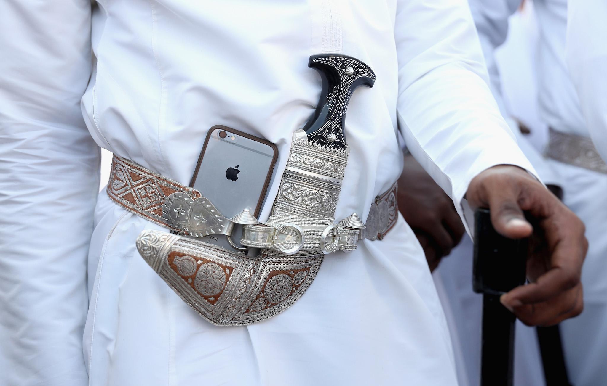 A dancer tucks his Apple iphone next to his traditional Omani dagger during an Omani cultural welcome ceremony outside the Sultan's Palace on the second day of a Royal tour of Oman on November 5, 2016 in Muscat, Oman