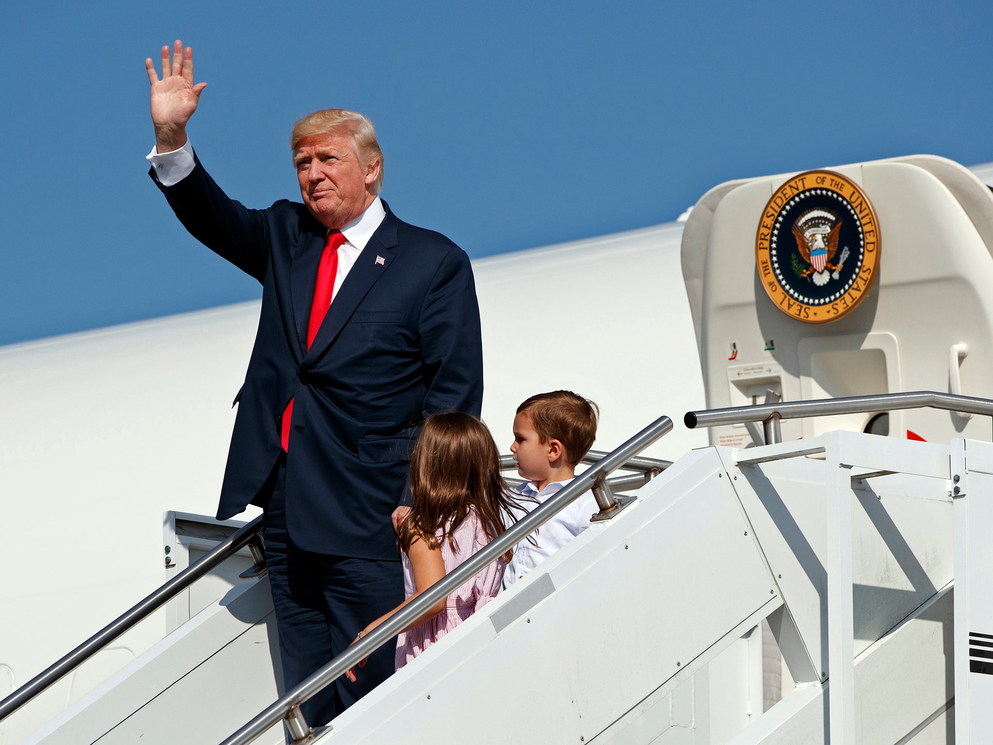 Donald Trump waves as he walks down the steps of Air Force One