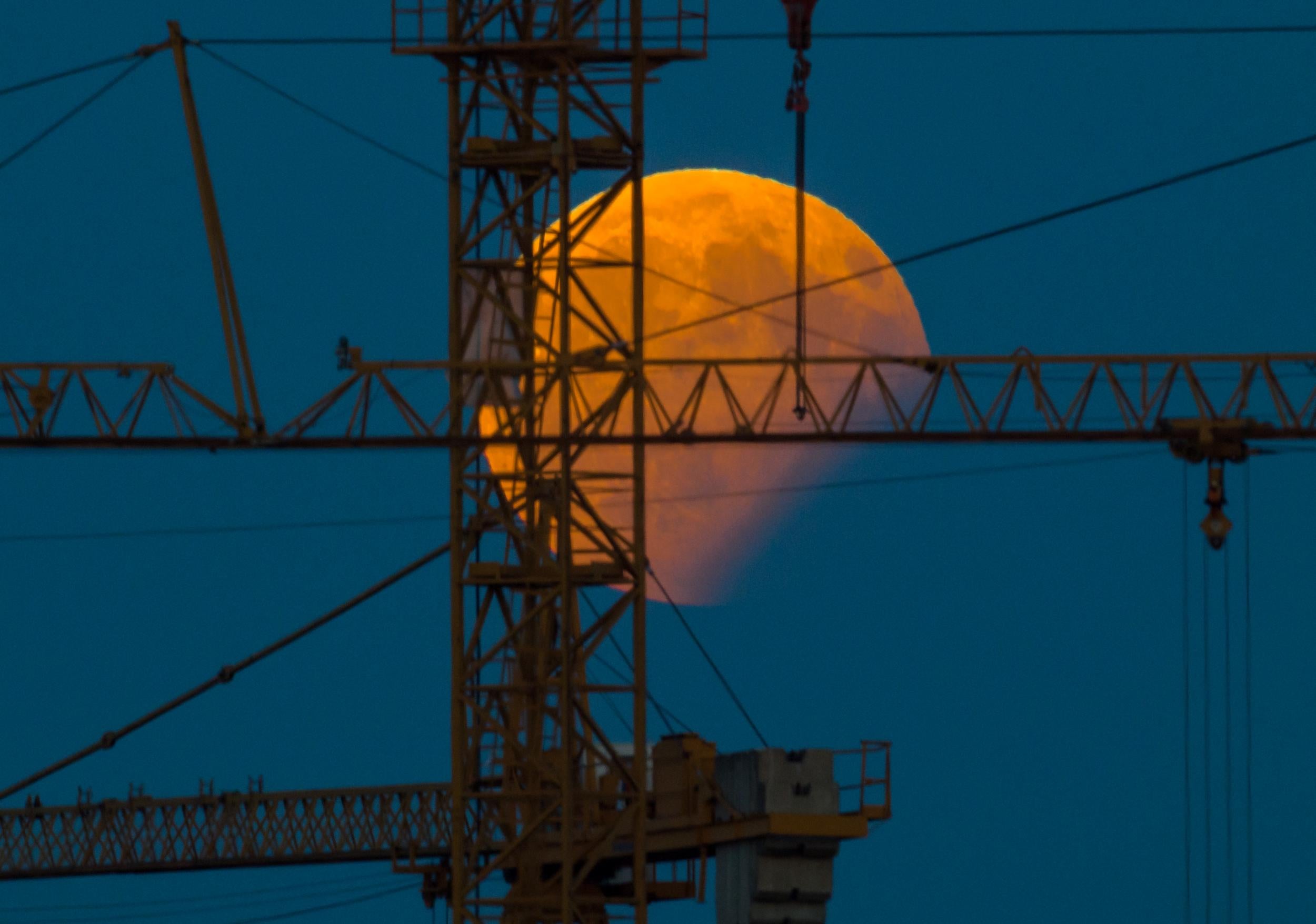 The moon standing in a partial lunar eclipse can be seen behind a constructin crane on August 7, 2017 in Gilching, southern Germany