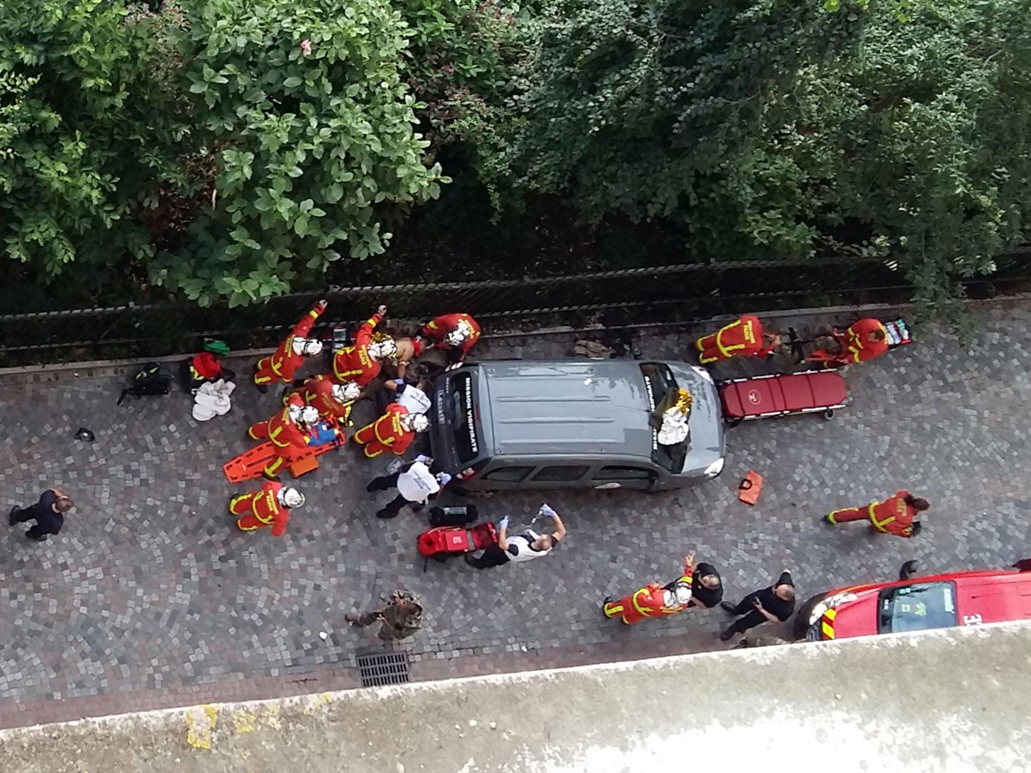 Officials and rescuers gather near vehicles after a car slammed into soldiers on patrol in Levallois-Perret
