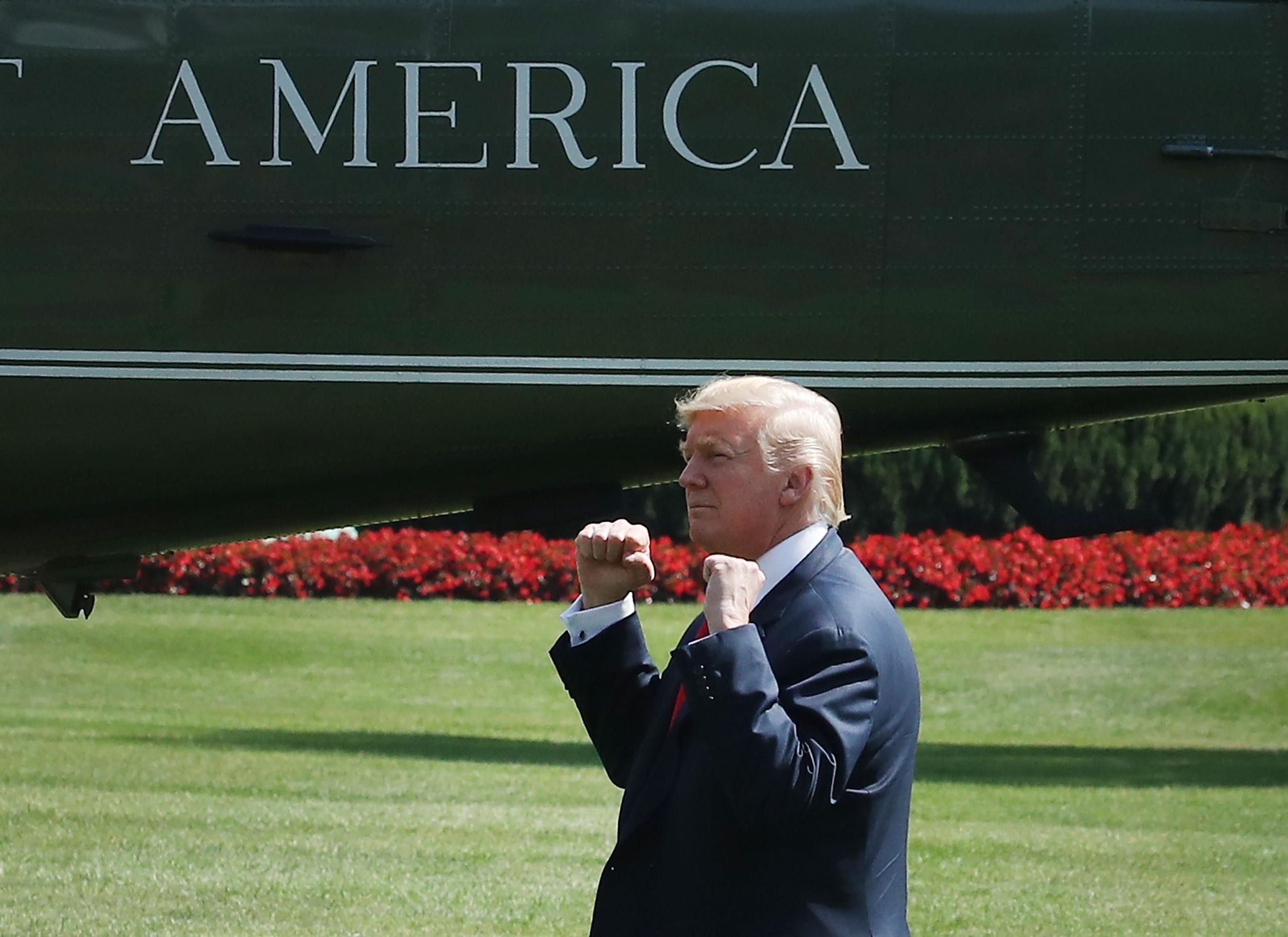 President Donald Trump gestures to a crowd gathered to watch him depart on Marine One for Bedminster