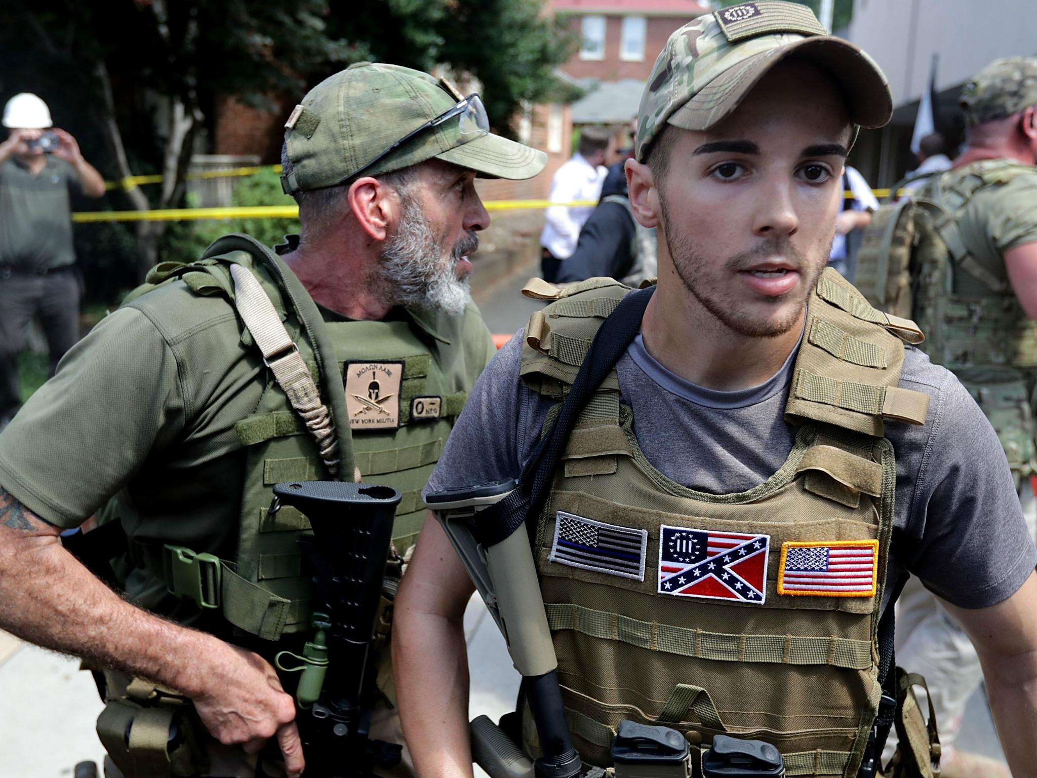 White nationalists, neo-Nazis and members of the 'alt-right' with body armor and combat weapons evacuate comrades who were pepper sprayed after the 'Unite the Right' rally was declared a unlawful gathering by Virginia State Police