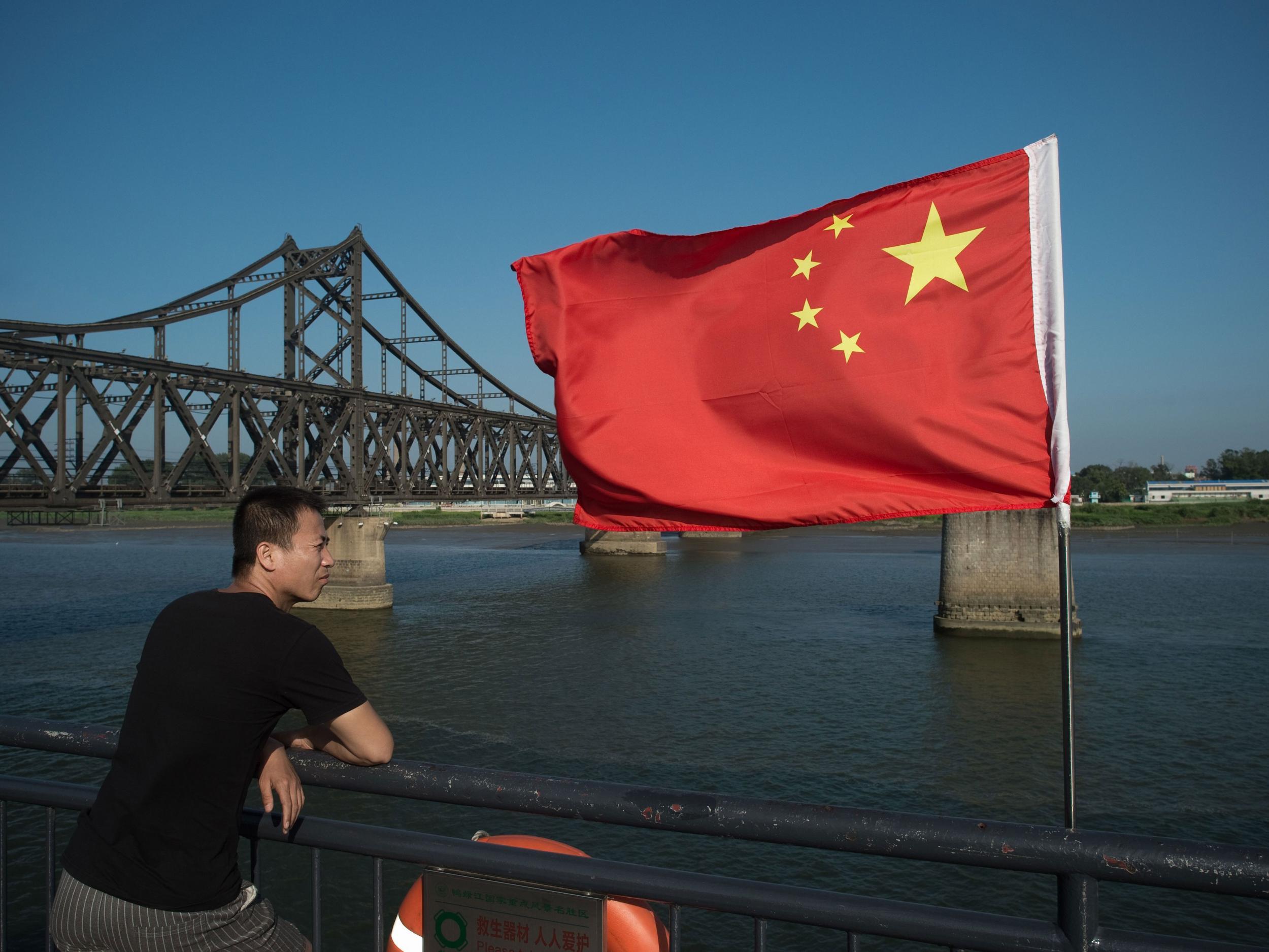 A tourist looks out from the Broken Bridge next to the Friendship bridge on the Yalu River connecting the North Korean town of Sinuiju and the Chinese border city of Dandong