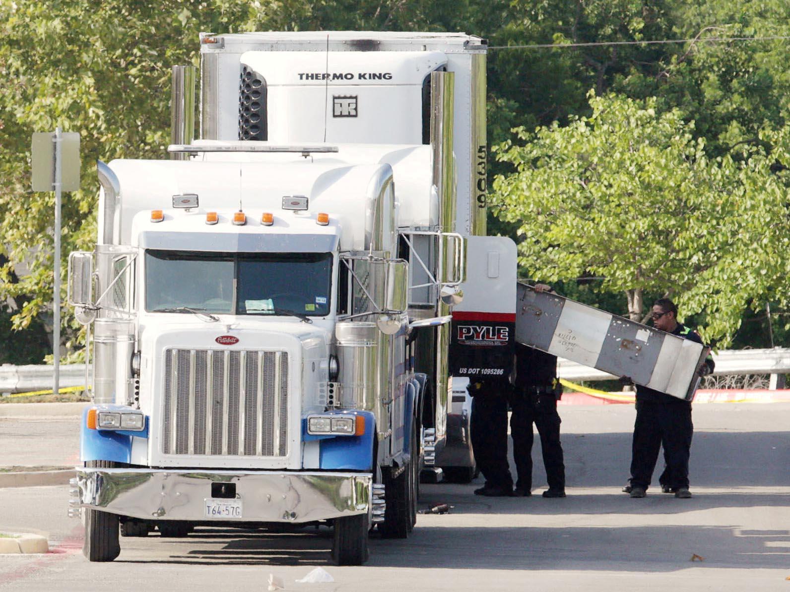 Police officers working at the crime scene after 10 people believed to be illegal immigrants being smuggled into the United States were found dead inside a sweltering 18-wheeler trailer parked behind a Walmart store in San Antonio, Texas, on 23 July 2017