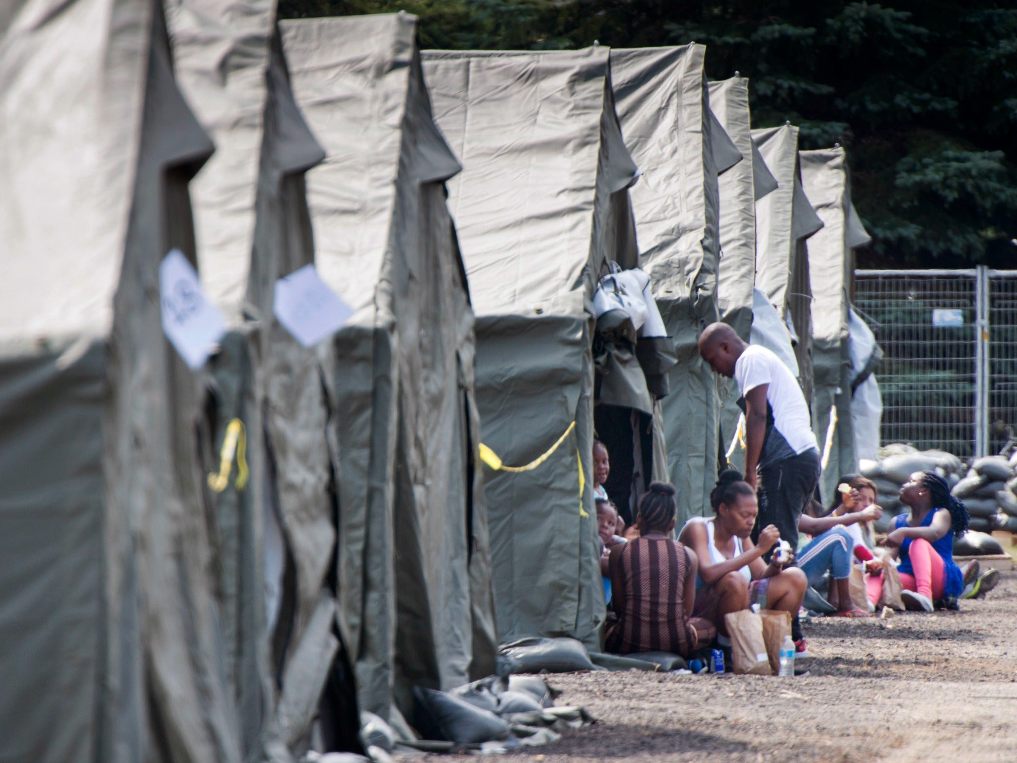 Asylum seekers sit in front of their tent in a temporary camp in Quebec, which has seen a surge in asylum-seekers, on Tuesday, Aug. 15, 2017.