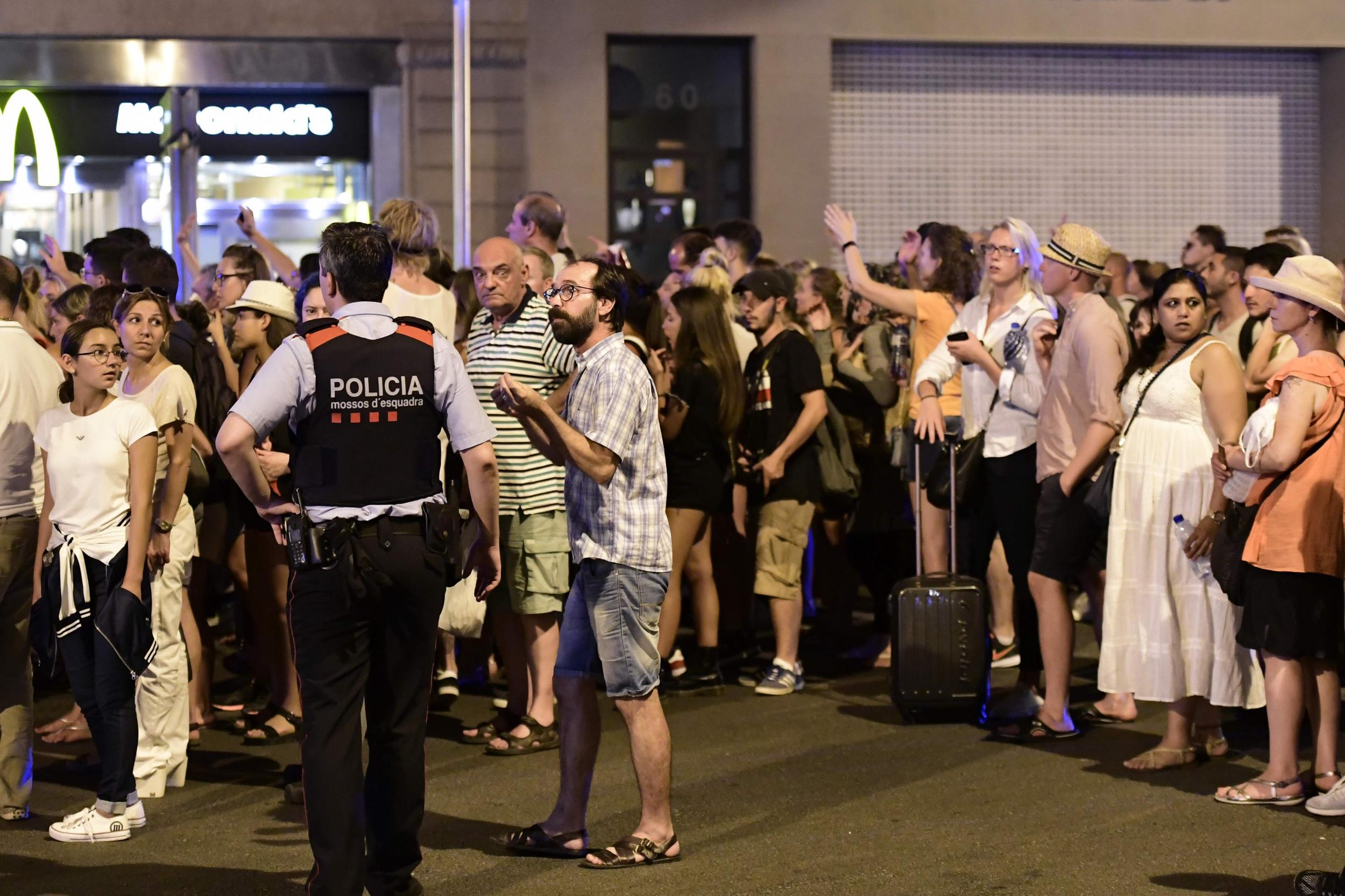 Tourists wait for the police to allow them to come back to their hotel on the Rambla boulevard