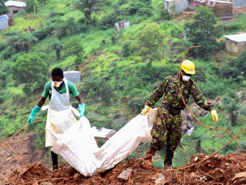 A body is recovered from the mud by rescue workers