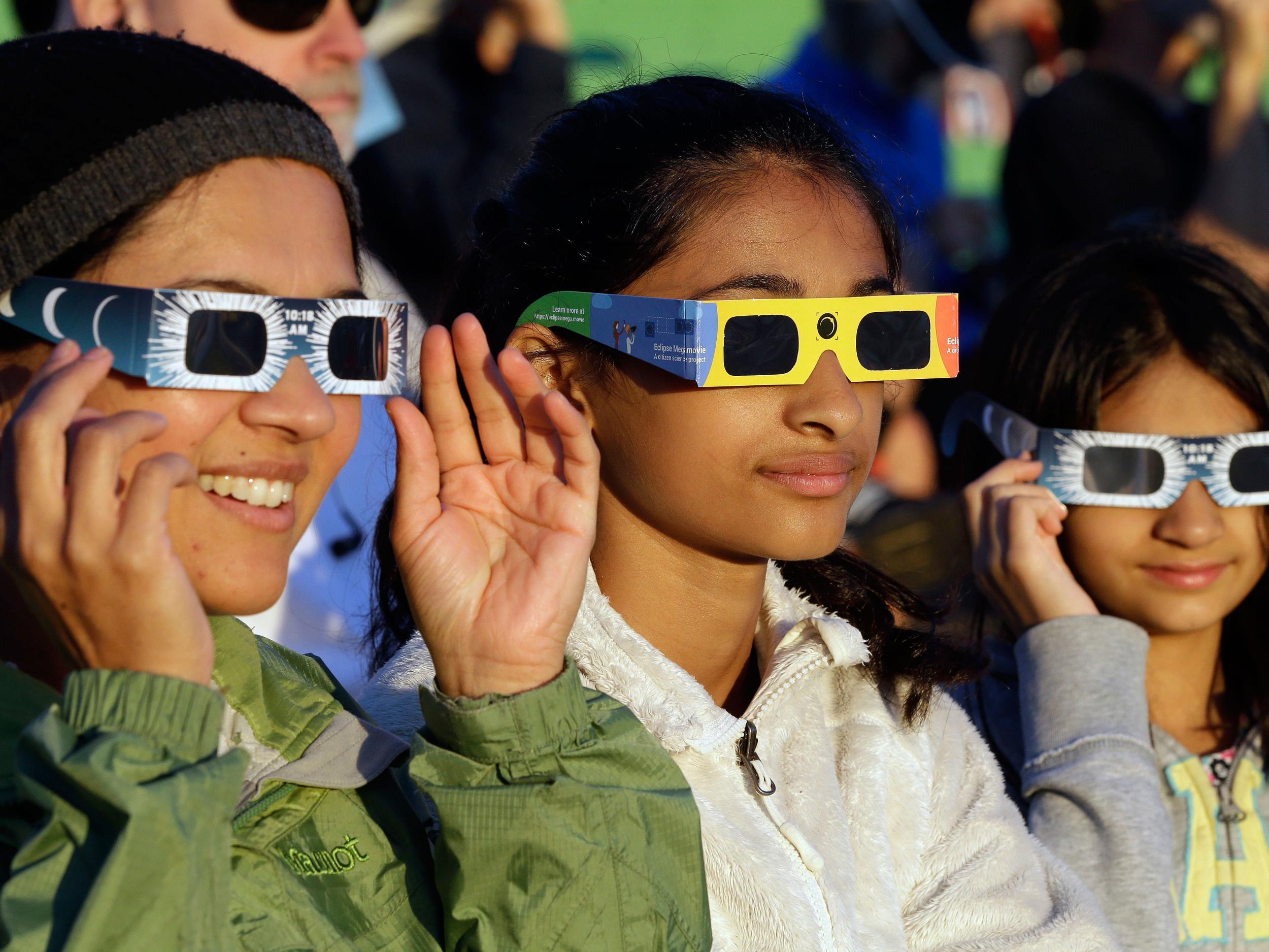 Visitors from Seattle try out their eclipse glasses on the sun at a gathering of eclipse viewers in Salem, Oregon