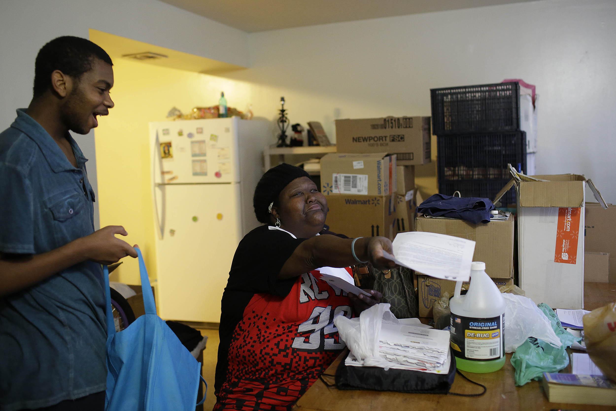 Demetra Turner reads a letter demanding she vacate her apartment as her son Jeremiah Kinley looks on